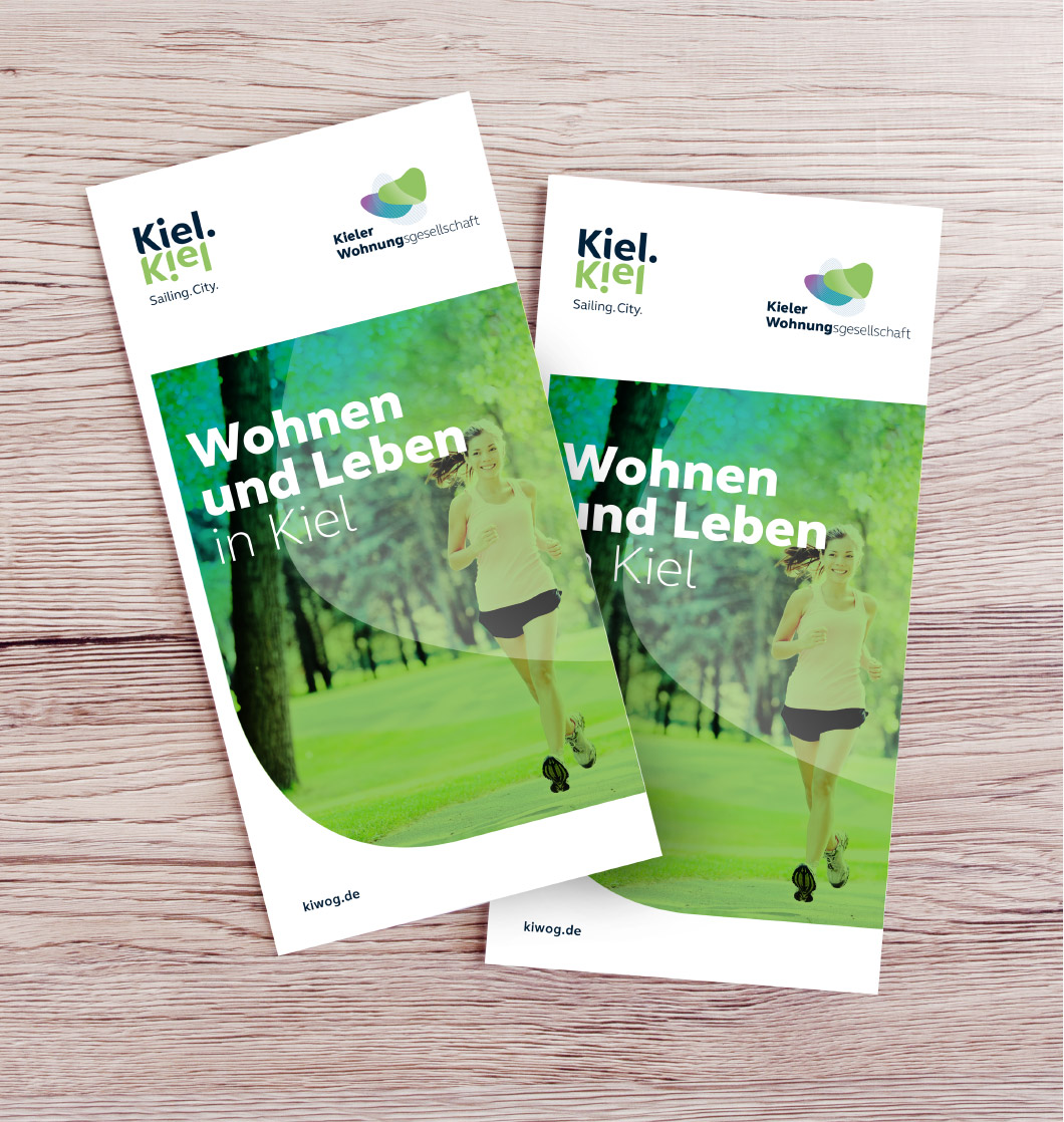 kiwog-03.jpg Zwei Flyer von kiwog auf Holztisch