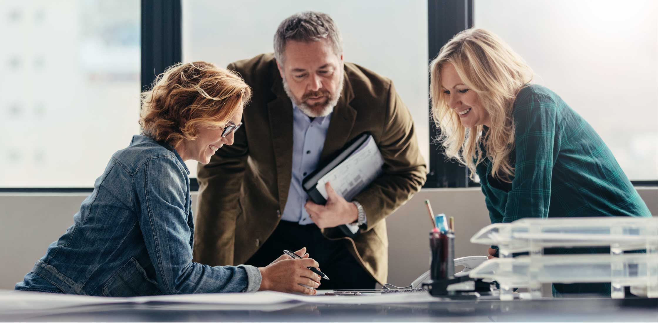 projectanalysts-08.jpg Drei Personen im Anzug schauen auf Papier