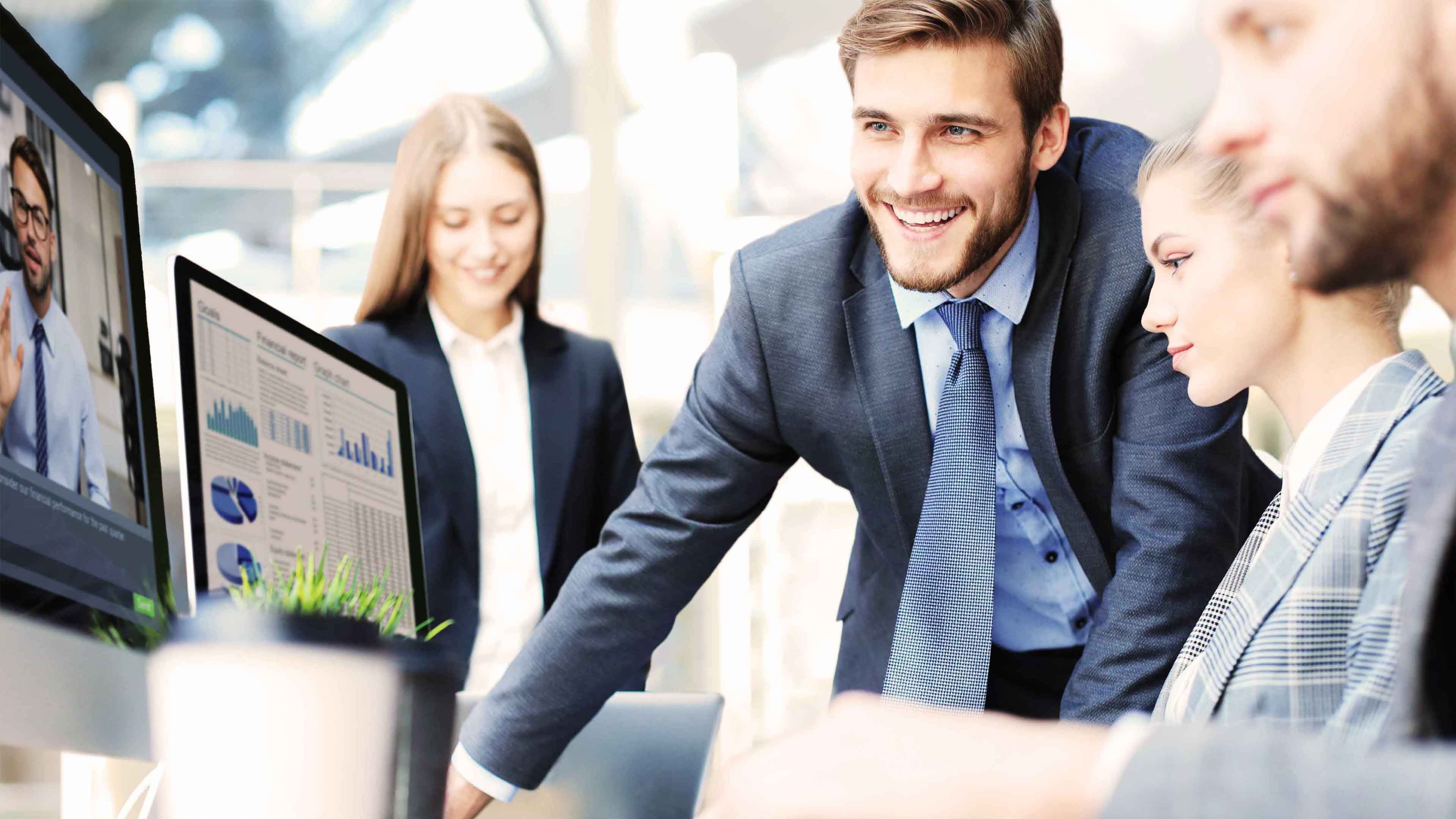 Vier Personen im Anzug gucken auf Computer