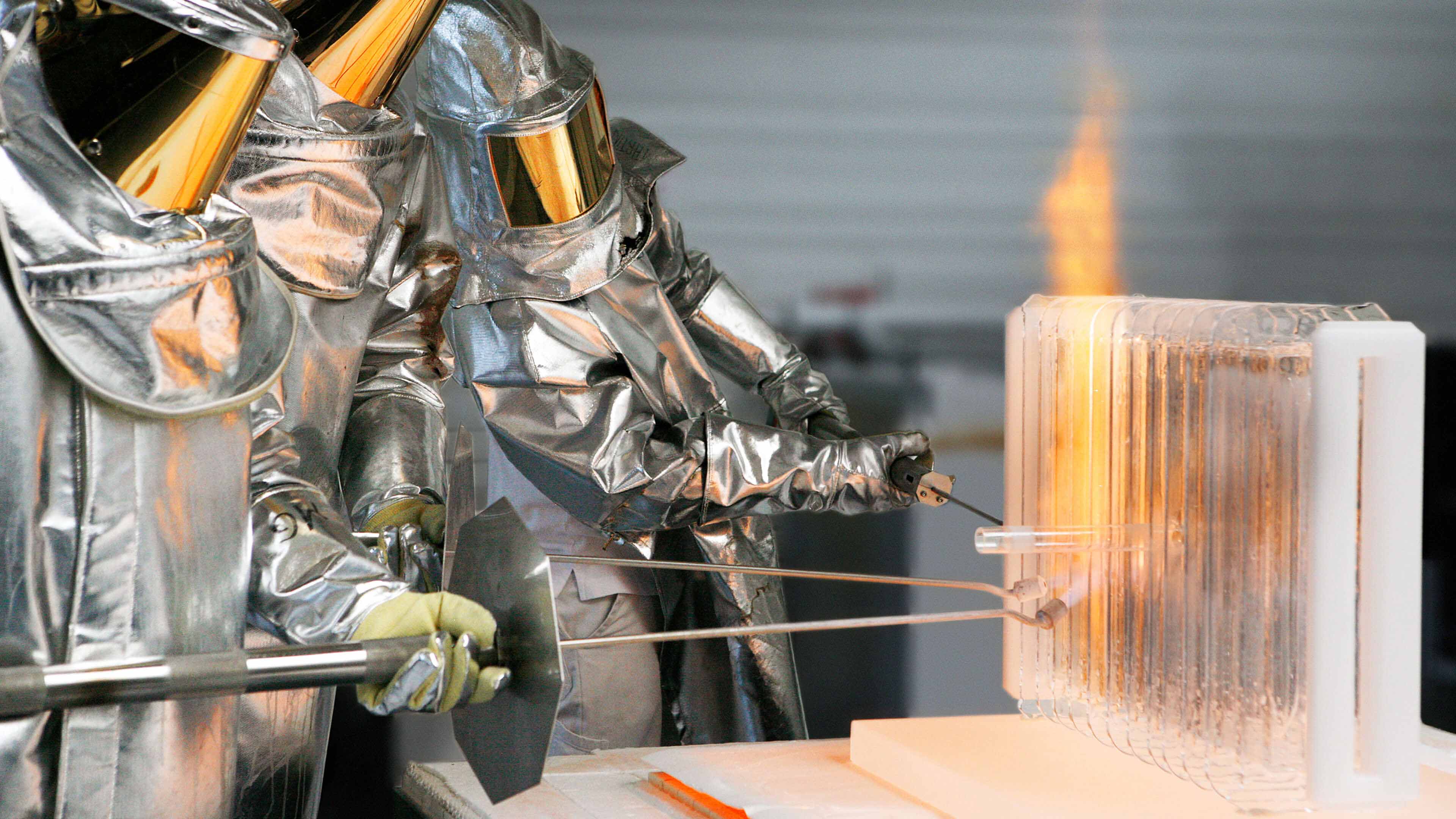 Drei Personen in silbernen Schutzanzügen