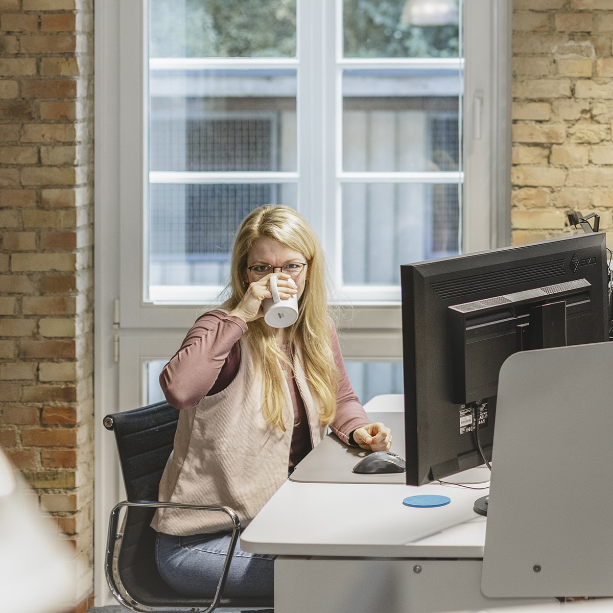 Mitarbeiterin des Teams Online Marketing bei HOCHZWEI trinkt aus Becher und blickt in die Kamera