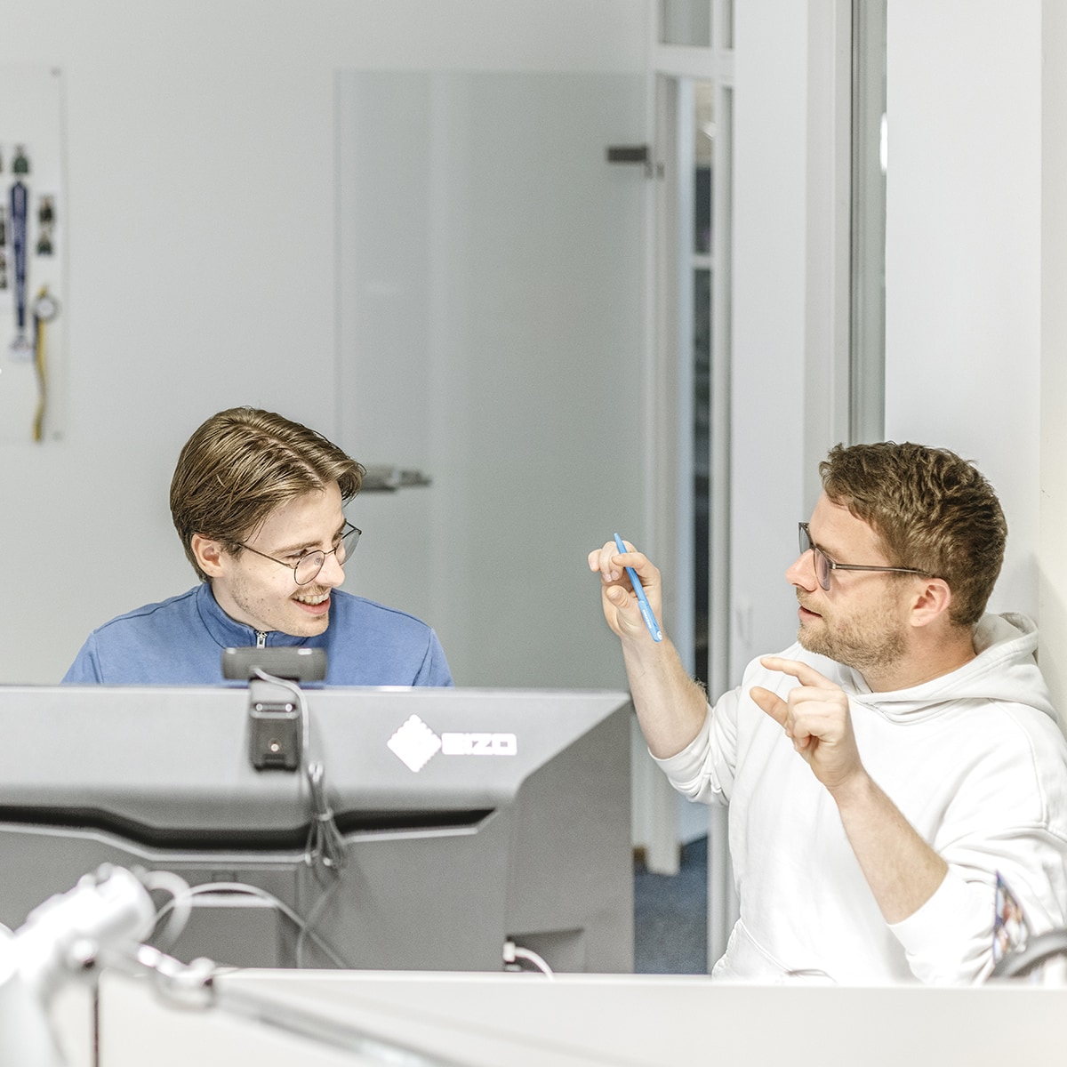 Zwei Grafiker im Arbeitsgespräch an einem Schreibtisch