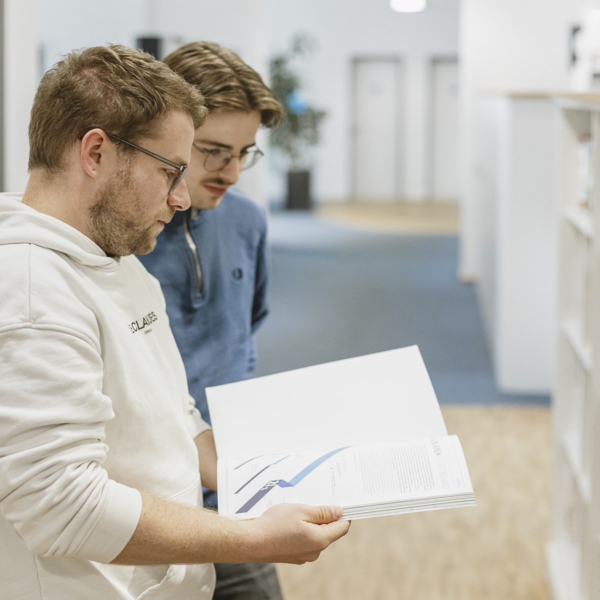 hochzwei-mitarbeitermotiv_M9A2092.jpg Zwei Mitarbeiter von HOCHZWEI blicken gemeinsam in ein Printkatalog