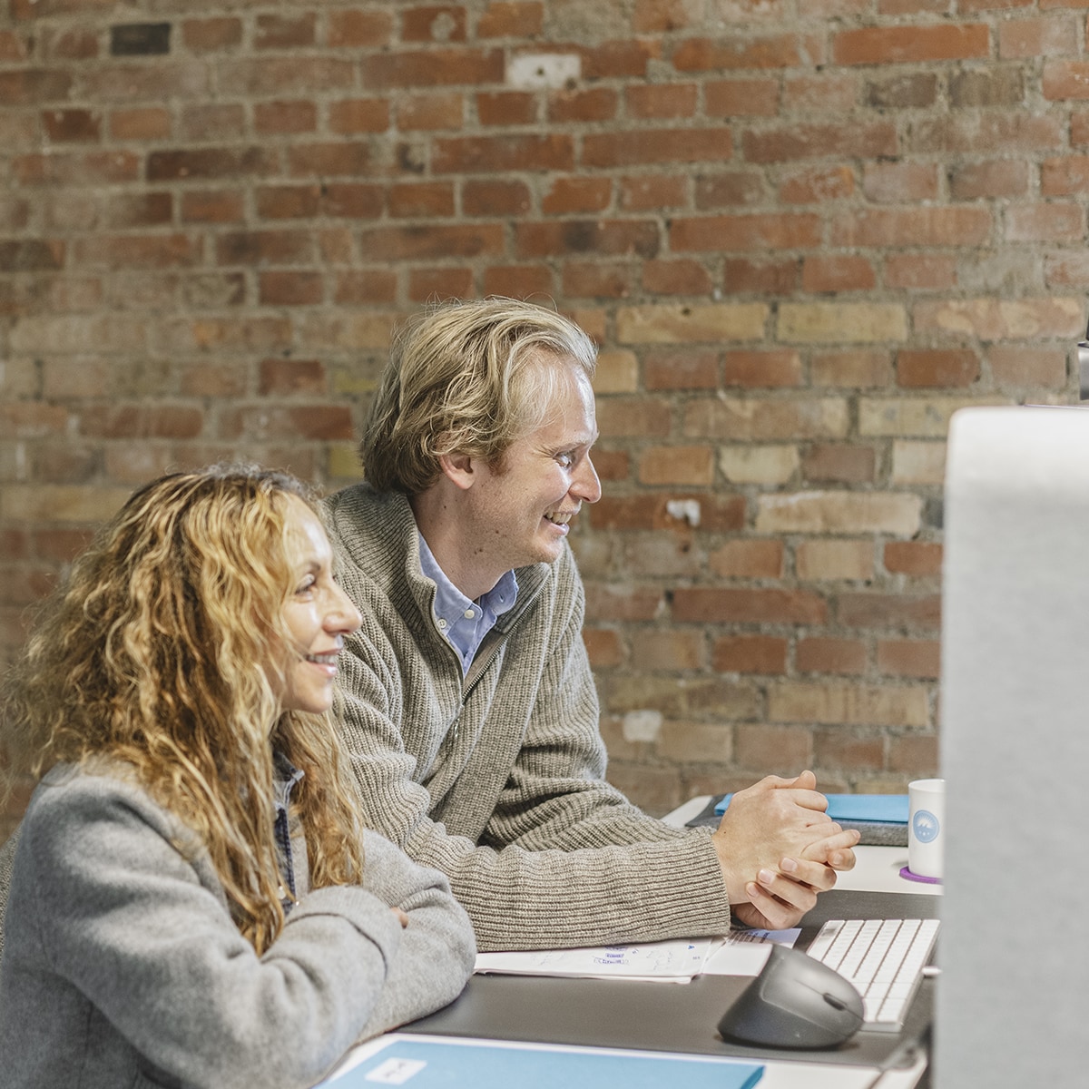 Zwei Mitarbeiter von HOCHZWEI blicken gemeinsam auf einen PC