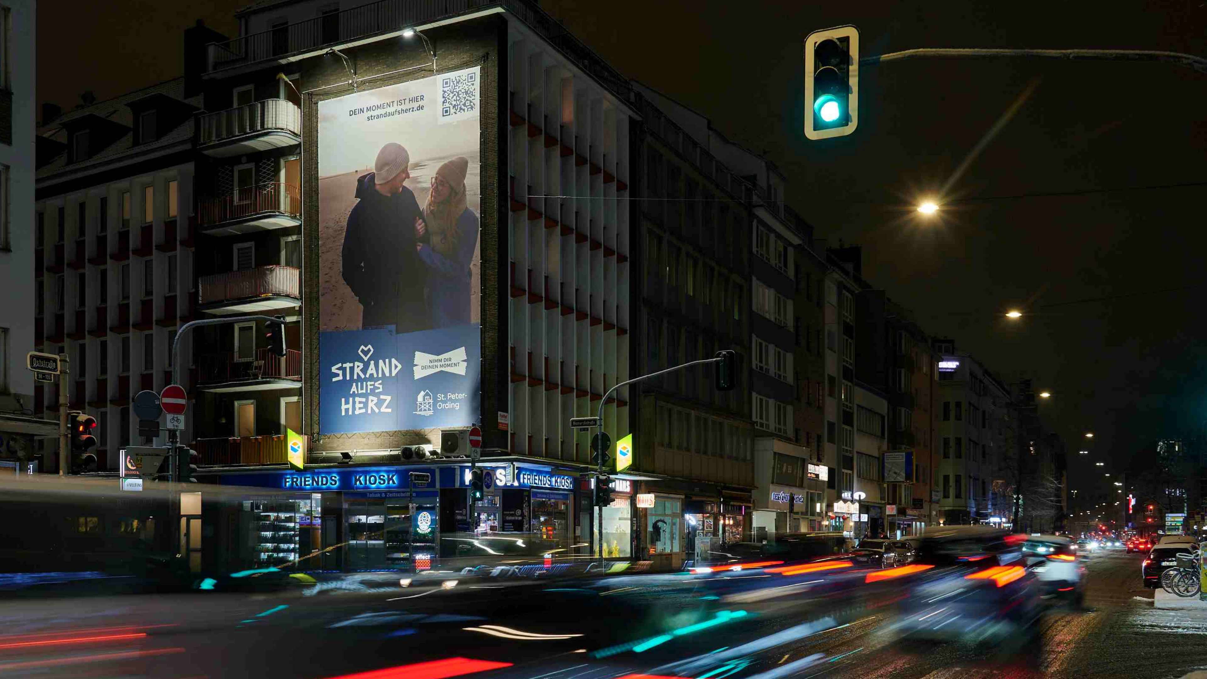 Ein riesiges Strand aufs Herz Plakat an einem Haus an einer Straße