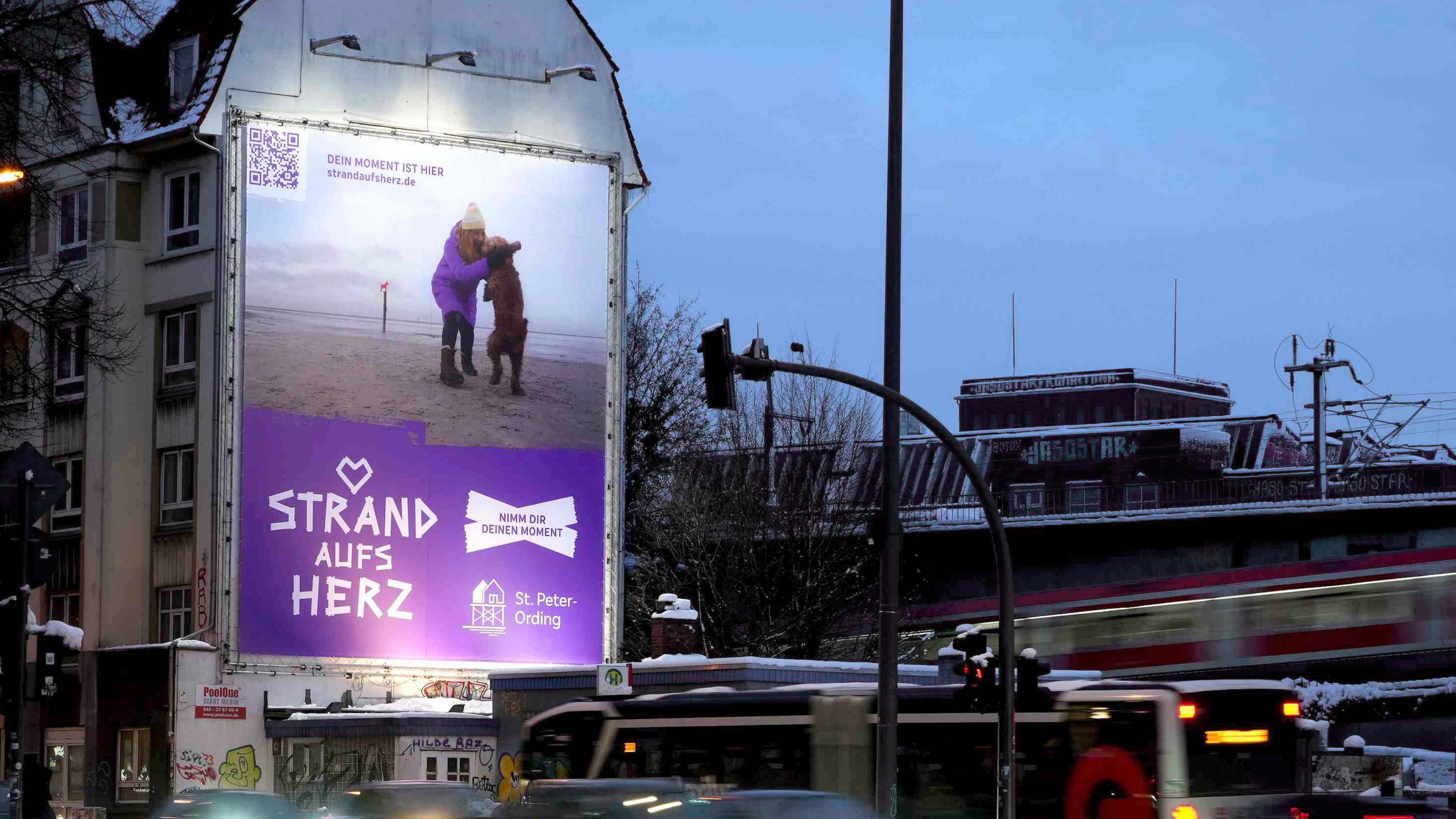 Ein riesiges Strand aufs Herz Plakat an einem Haus an einer Straße