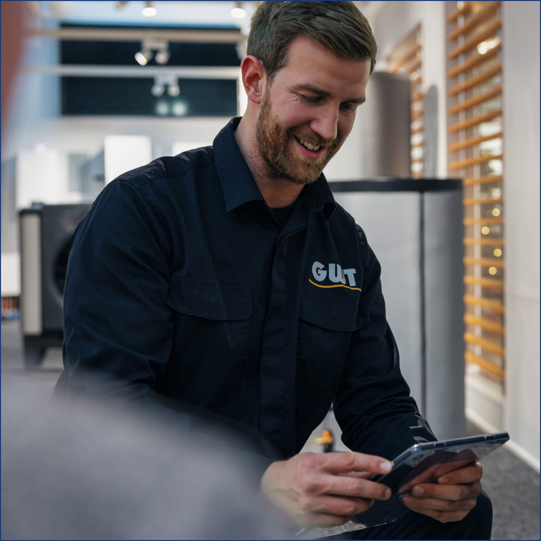 hochzwei_Internetauftritt_GWT_teaser_09.jpg Ein schwarz gekleideter Handwerker schaut lächelnd auf ein iPad