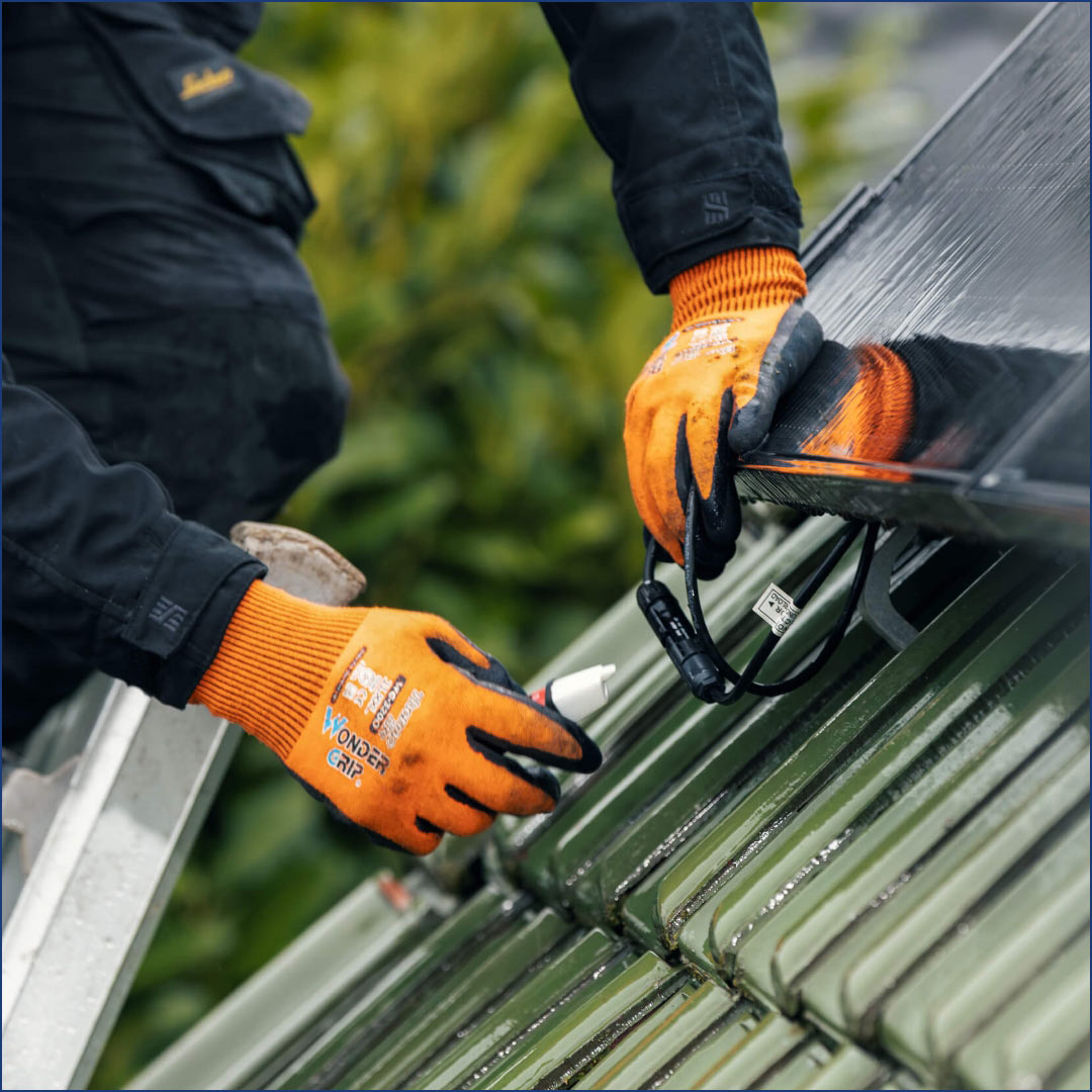 hochzwei_Internetauftritt_GWT_teaser_10.jpg Ein Mann trägt zwei orangene Handschuhe und arbeitet auf einem Dach
