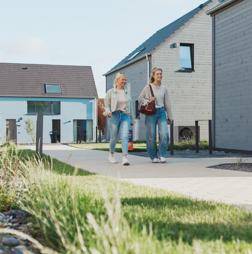 h2_gstolz_teaser_05.jpg Zwei blonde Frauen gehen zwischen modernen Häusern
