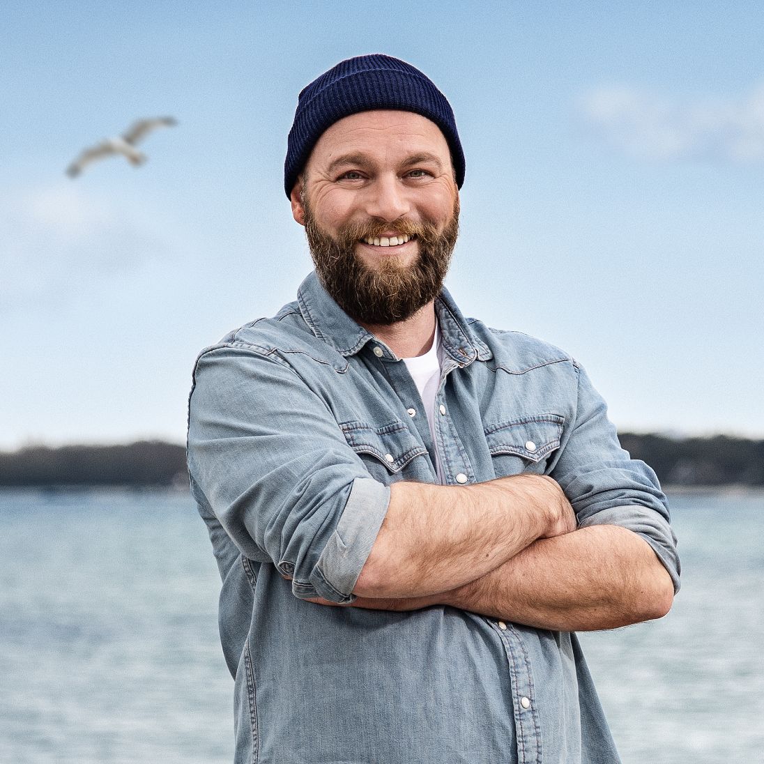 Mann mit Wollmütze am Strand