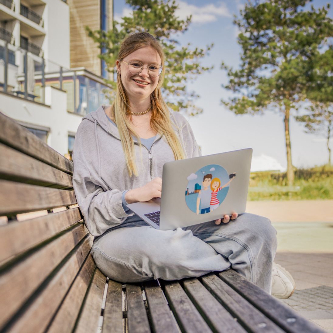 Junge Frau mit Laptop auf Bank