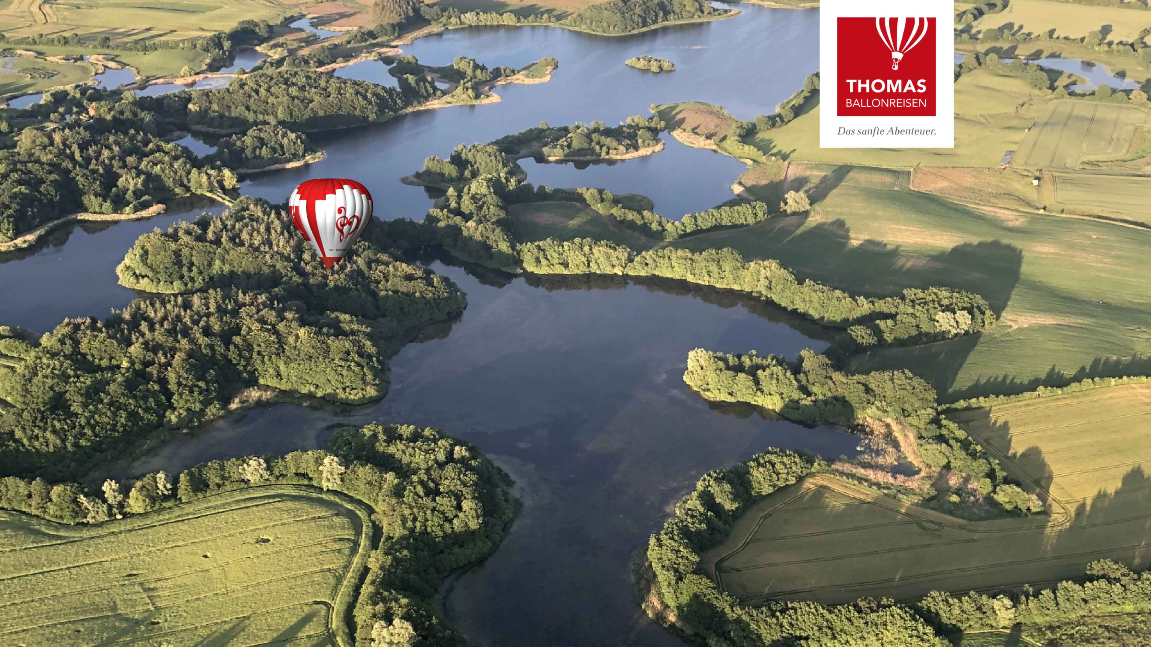 Luftaufnahme einer Seenlandschaft mit einem Heißluftballon