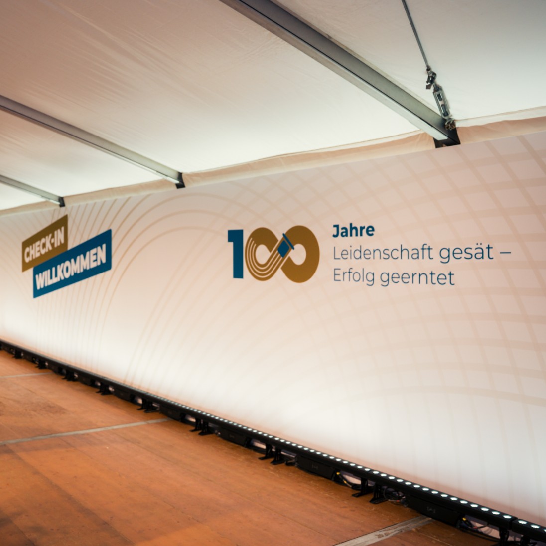 h2_einblicke_firmenevents_teaser_11.jpg Ansicht einer Pressewand mit Wüstenberg Logo und 100 Jahre Wüstenberg Text auf der Jubiläumsfeier von Wüstenberg.
