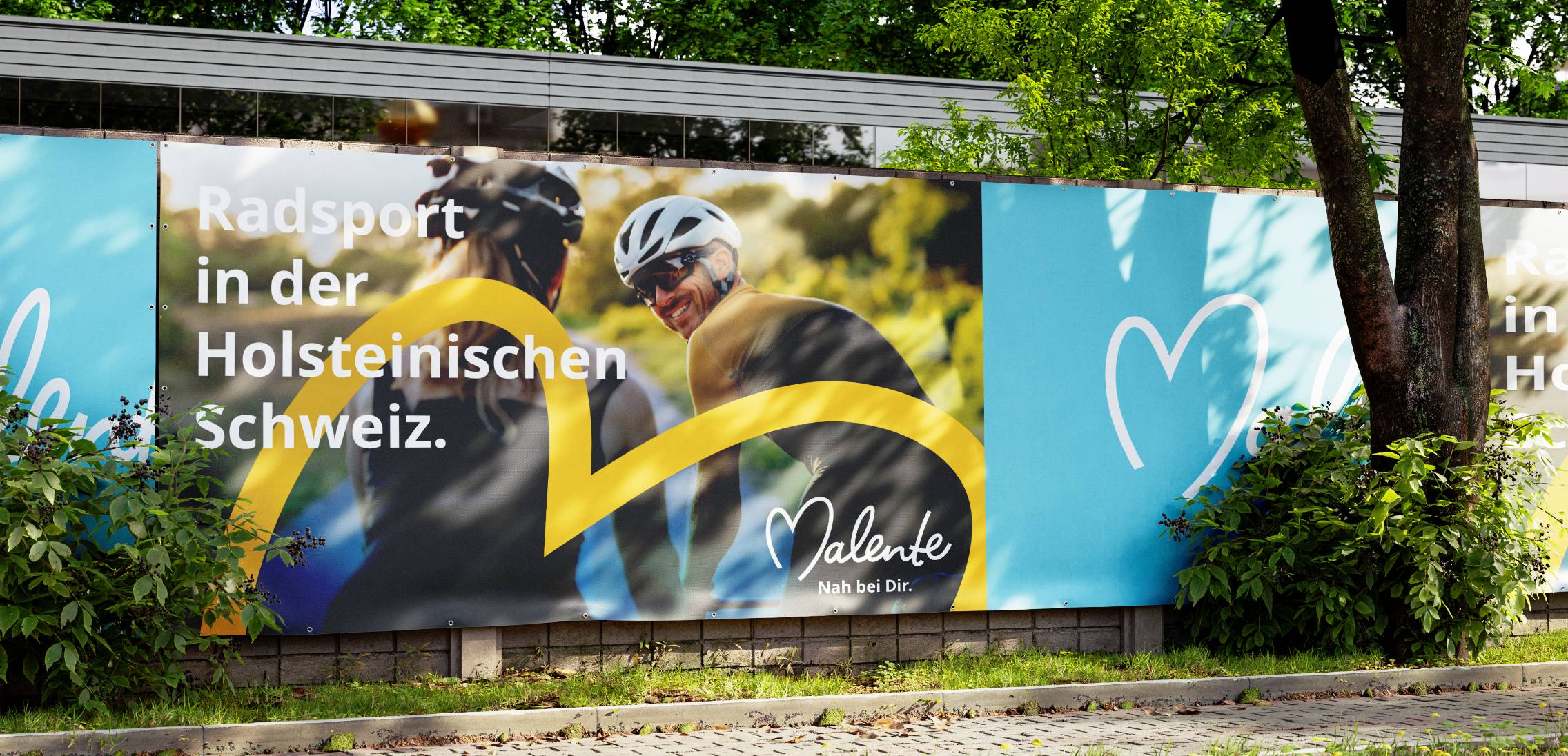 Eine Plakatwand im Grünen mit zwei Radfahrern und dem Schriftzug Radsport in der Holsteinischen Schweiz