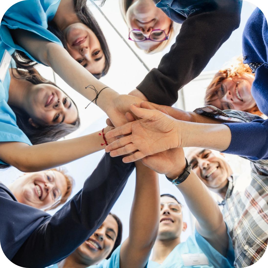 Acht Menschen stehen im Kreis und halten ihre Hände in der Mitte zusammen