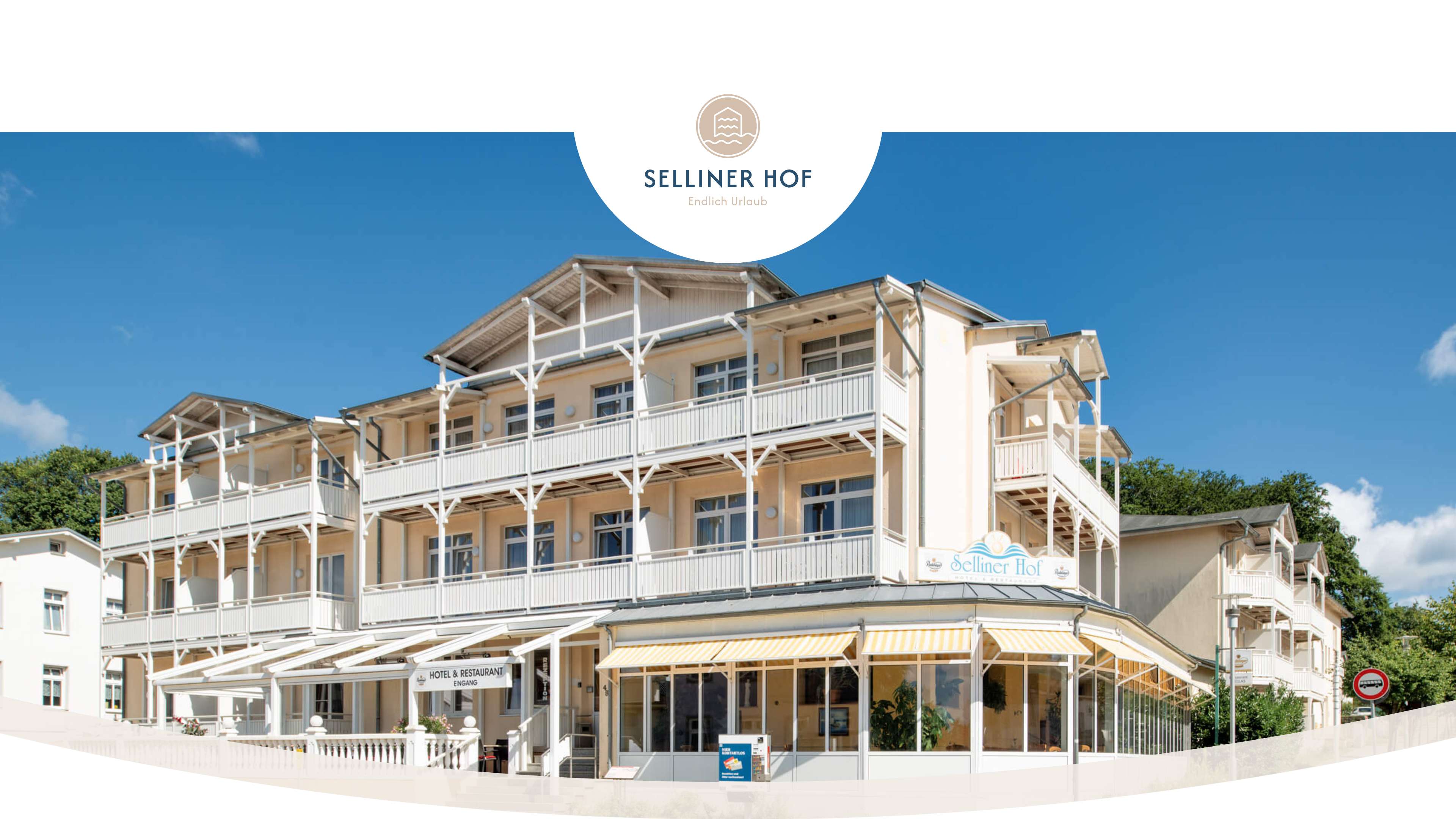 Ansicht des Selliner Hofes von der Straße bei Sonnenschein und wolkenlosem Himmel. Das Gebäude hat auf jeder Etage überdachte Balkone.