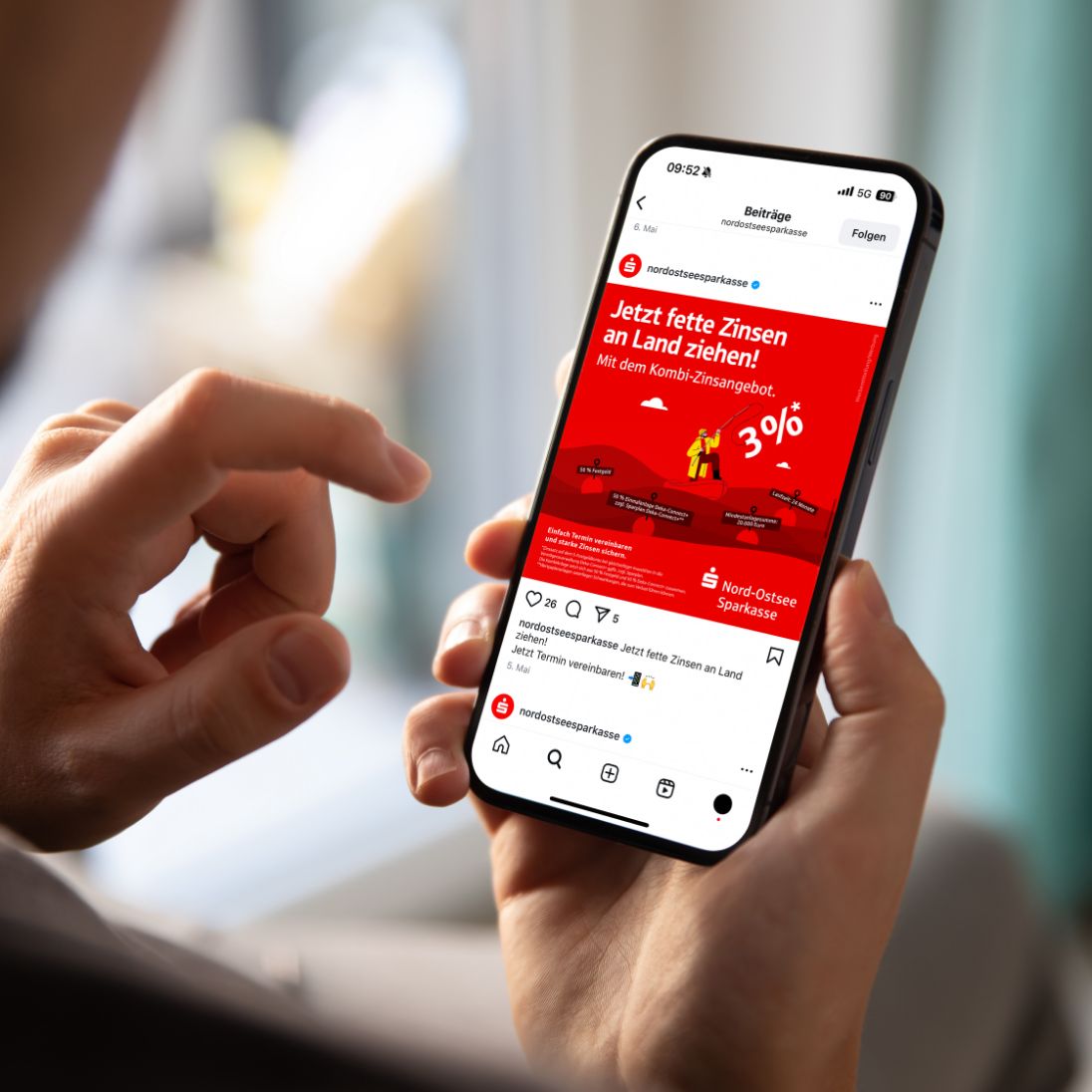 Hände halten Mobiltelefon, das Instagram Beitrag zum nospa-Zinsanker zeigt