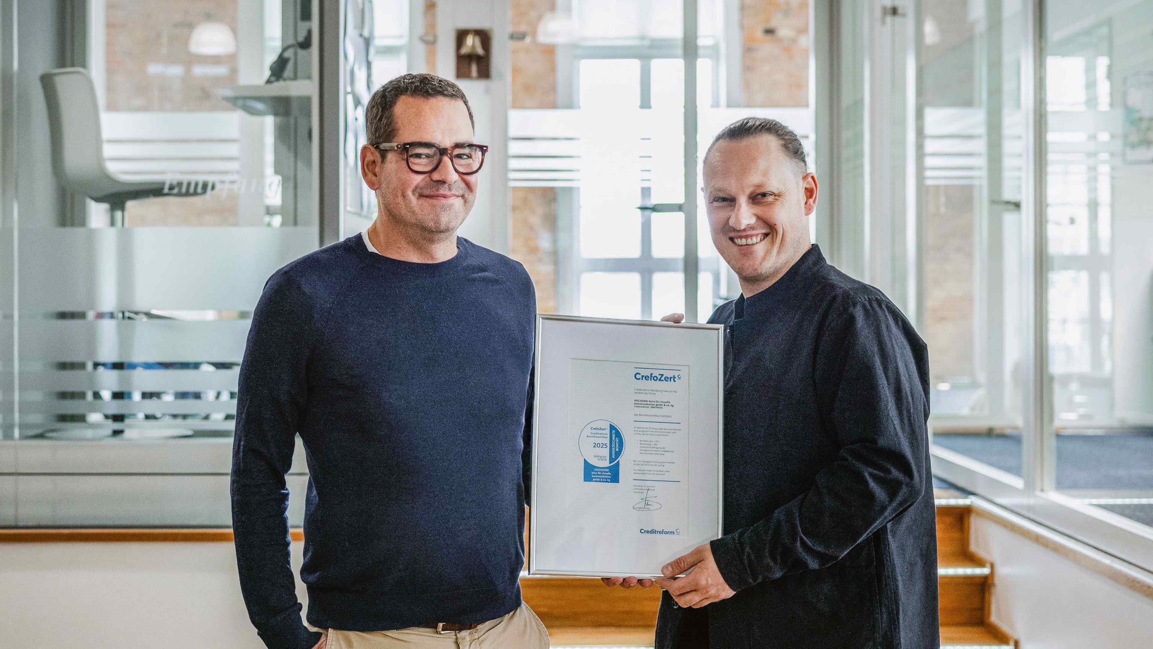 Geschäftsführer Felix Worm posiert mit dem Herrn von CrefoZert im Büro in Flensburg