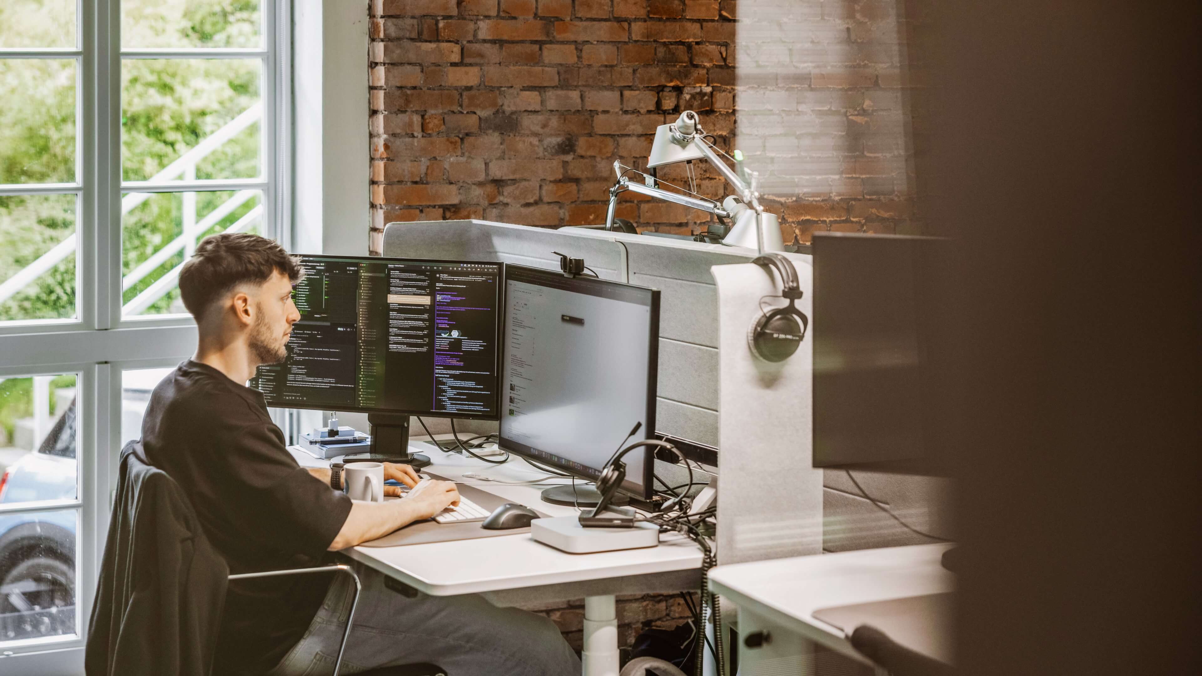 h2_crefozert_slider_02.jpg Ein Hochzwei Mitarbeiter arbeitet konzentriert an einem Schreibtisch mit zwei Bildschirmen.