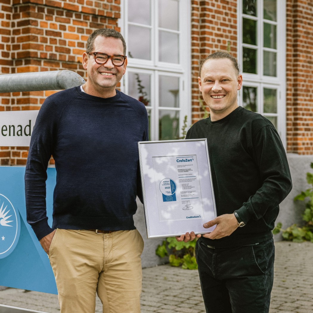 h2_crefozert_teaser_04.jpg Geschäftsführer Felix Worm posiert mit dem Herrn von CrefoZert vor dem Hochzwei Gebäude in Flensburg