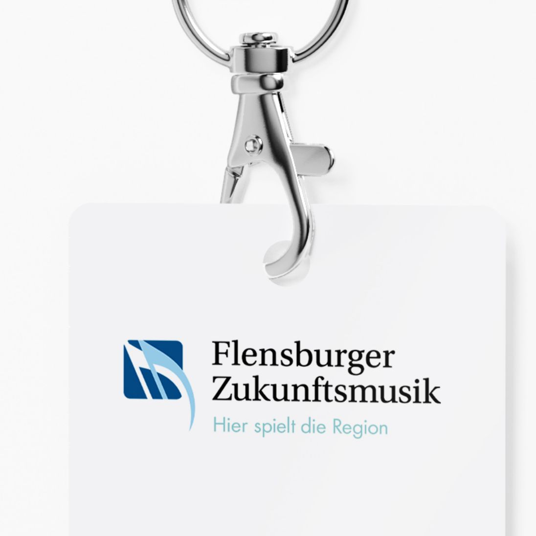 Karabiner mit Schildchen mit dem Schriftzug Flensburger Zukunftsmusik Hier spielt die Region, links daneben das Logo zwei Fähnchen von Noten