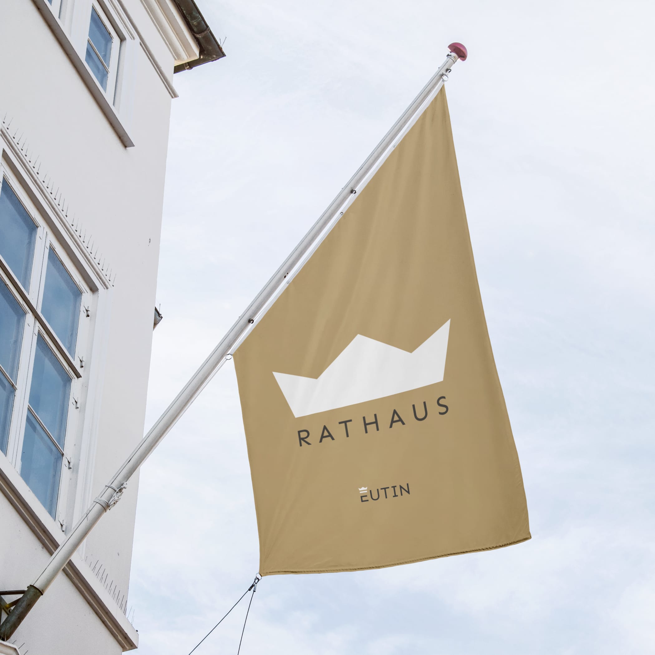 Fahnemast an Hausfassade mit Krone und Text 