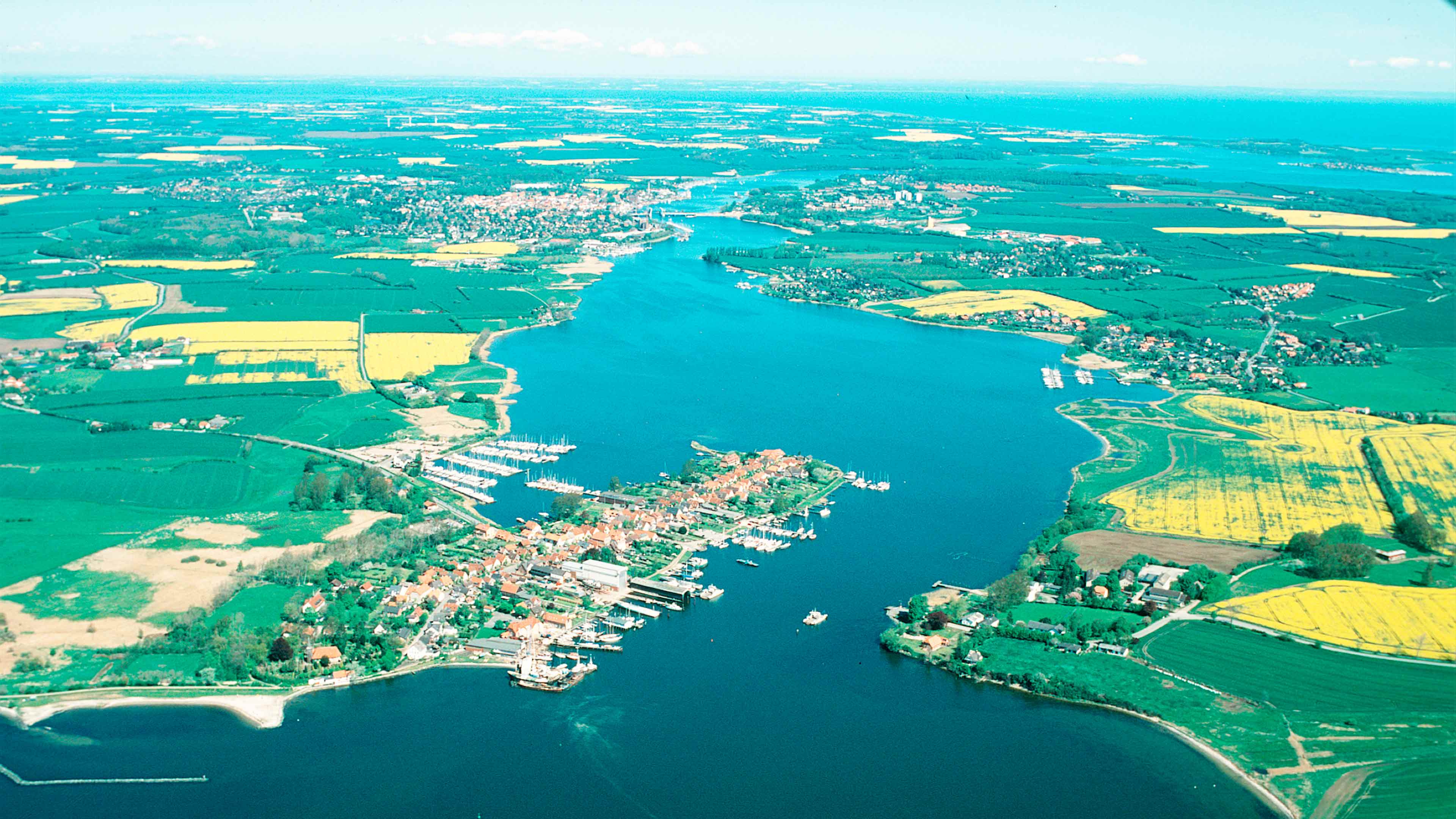 hochzwei_ffto_slider_02.jpg Luftaufnahme der Schlei mit Blick auf Arnis und Kappeln und Rapsfelder