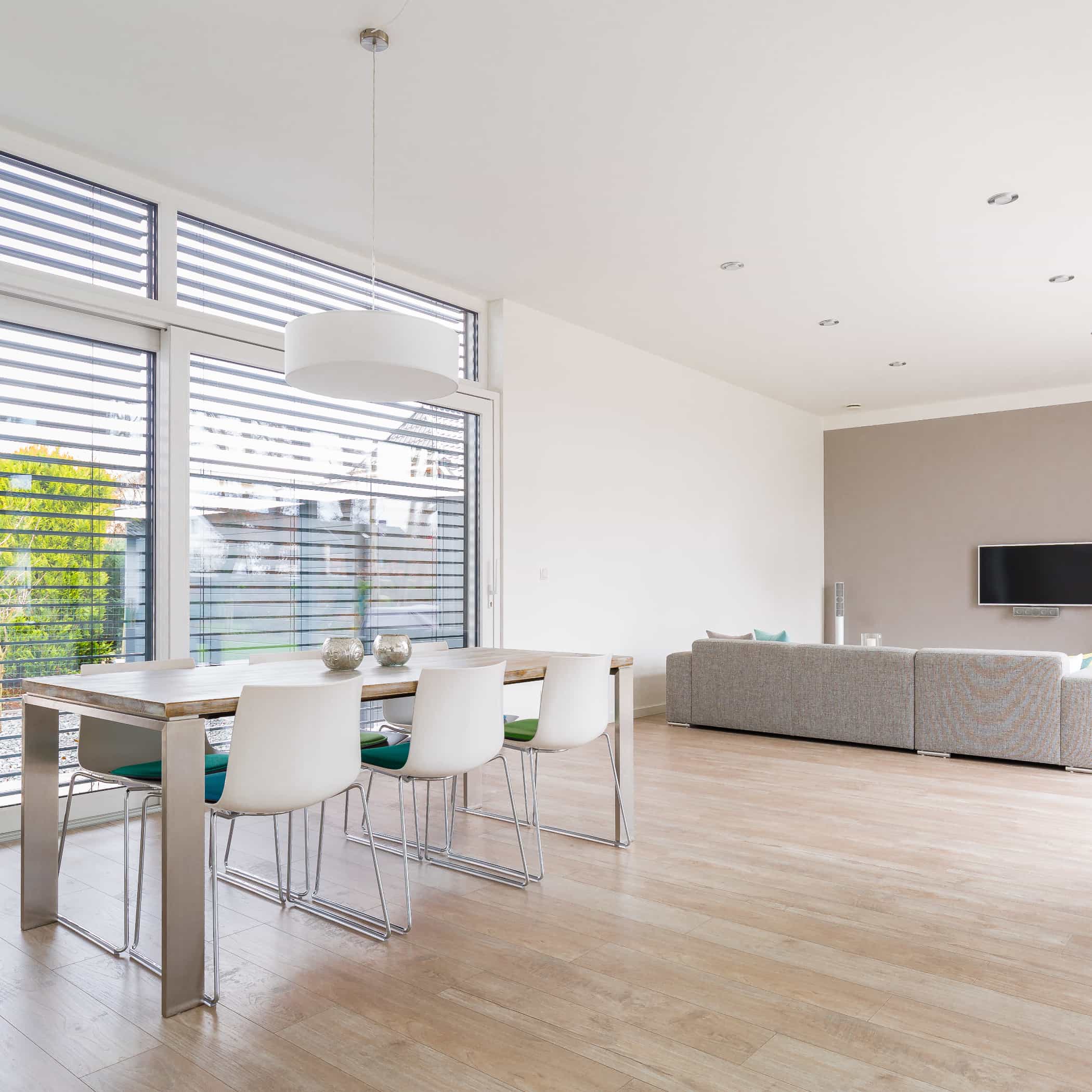 Modernes Wohnzimmer mit großem Fenster, Esstisch und Sofa auf Parkett