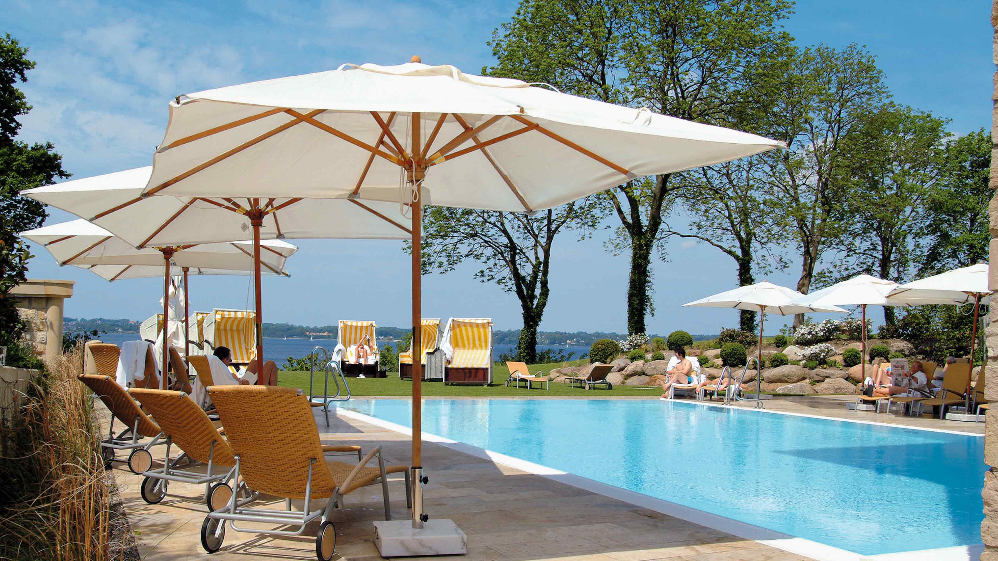 Swimming Pool, Sonnenschirme, gelbe Sonnenliegen und gelb-weiße Strandkörbe