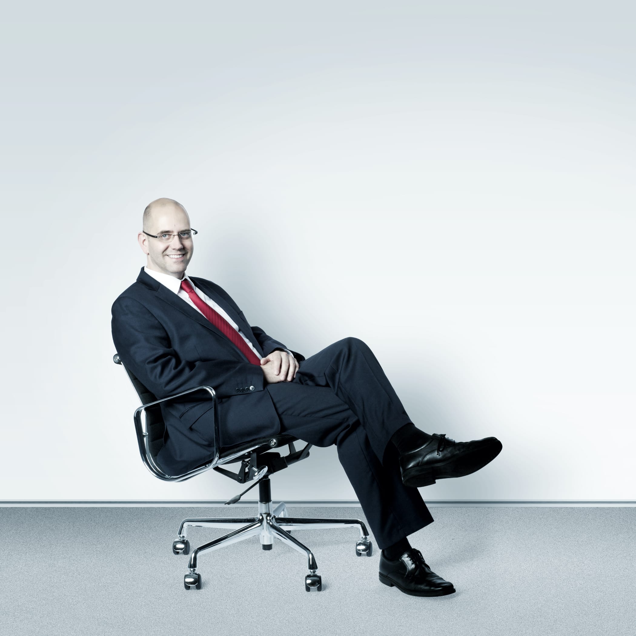 hochzwei_arbe_teaser_03.jpg Mann mit Brille und Anzug im Bürostuhl