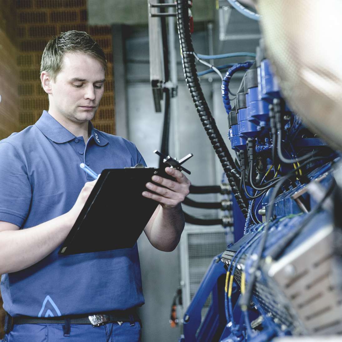 Ein Mann steht an einer Maschine und schreibt etwas auf ein Klemmbrett