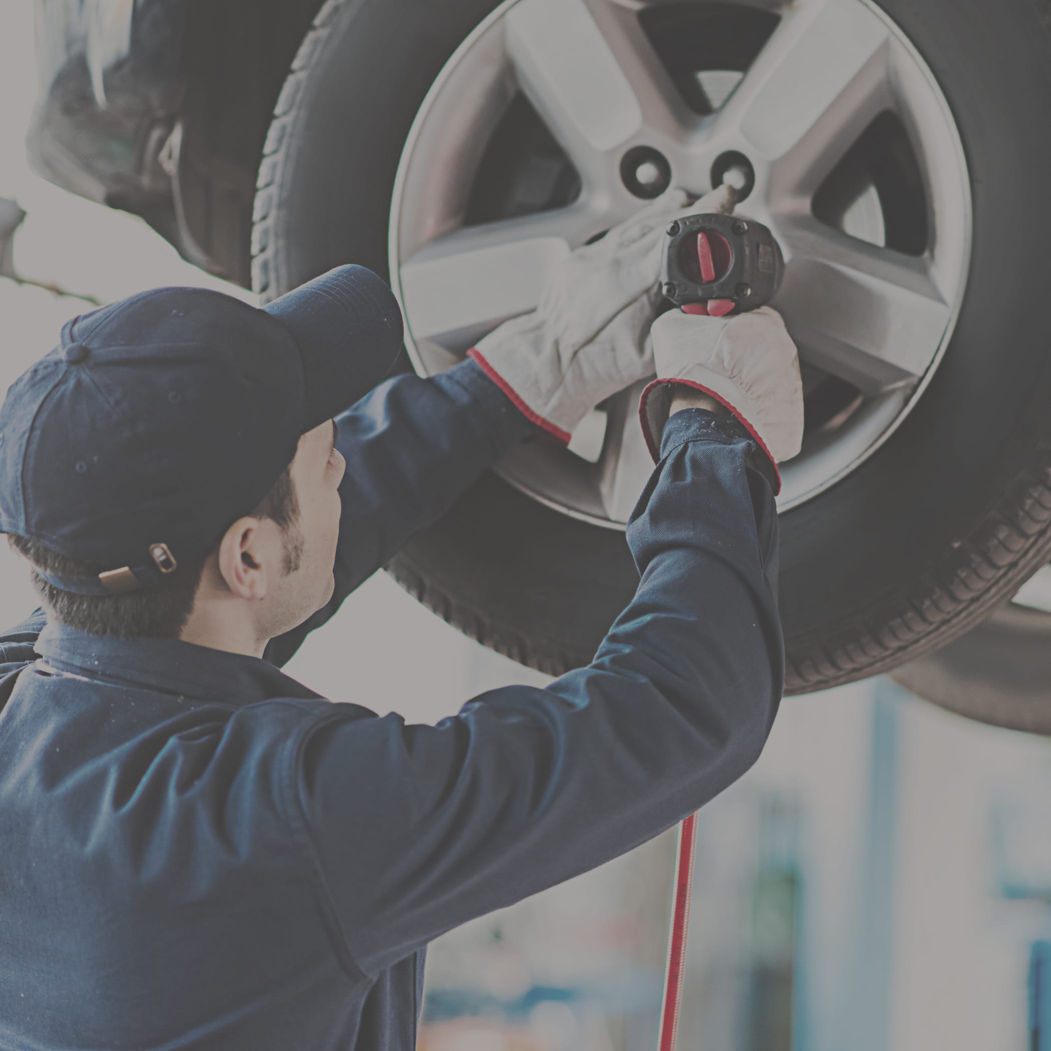 hochzwei_abau_teaser_07.jpg Ein Mann mit Schirmmütze schraubt an Radmuttern eines hohen Reifens