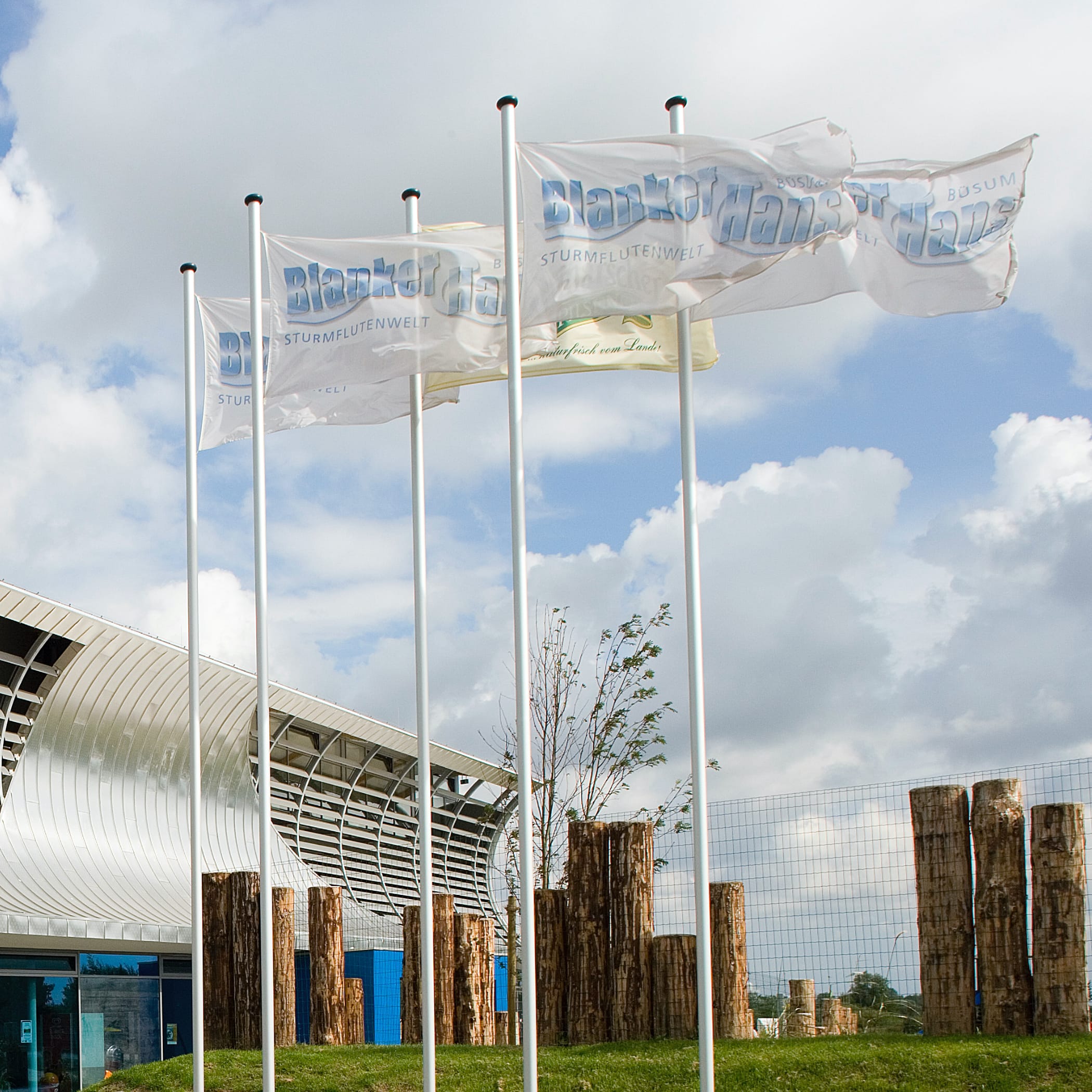 hochzwei_blah_teaser_07.jpg Fünf Fahnenmasten mit weißen Flaggen mit Blanker-Hans-Aufdruck