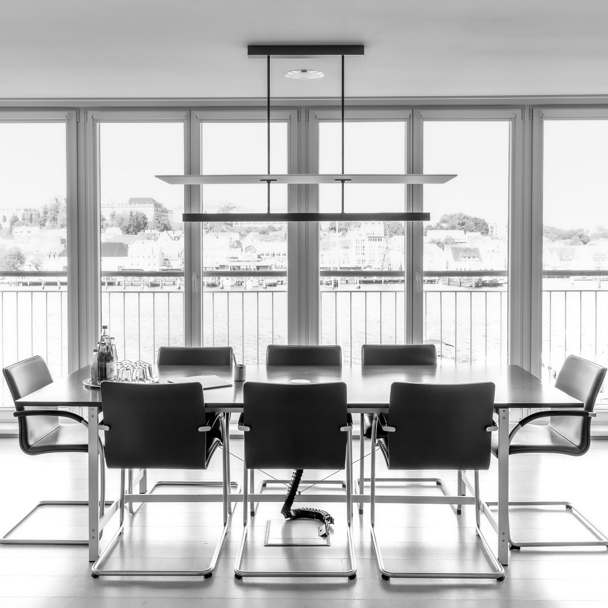 Langer Tisch mit 8 Stühlen vor einer Fensterfront