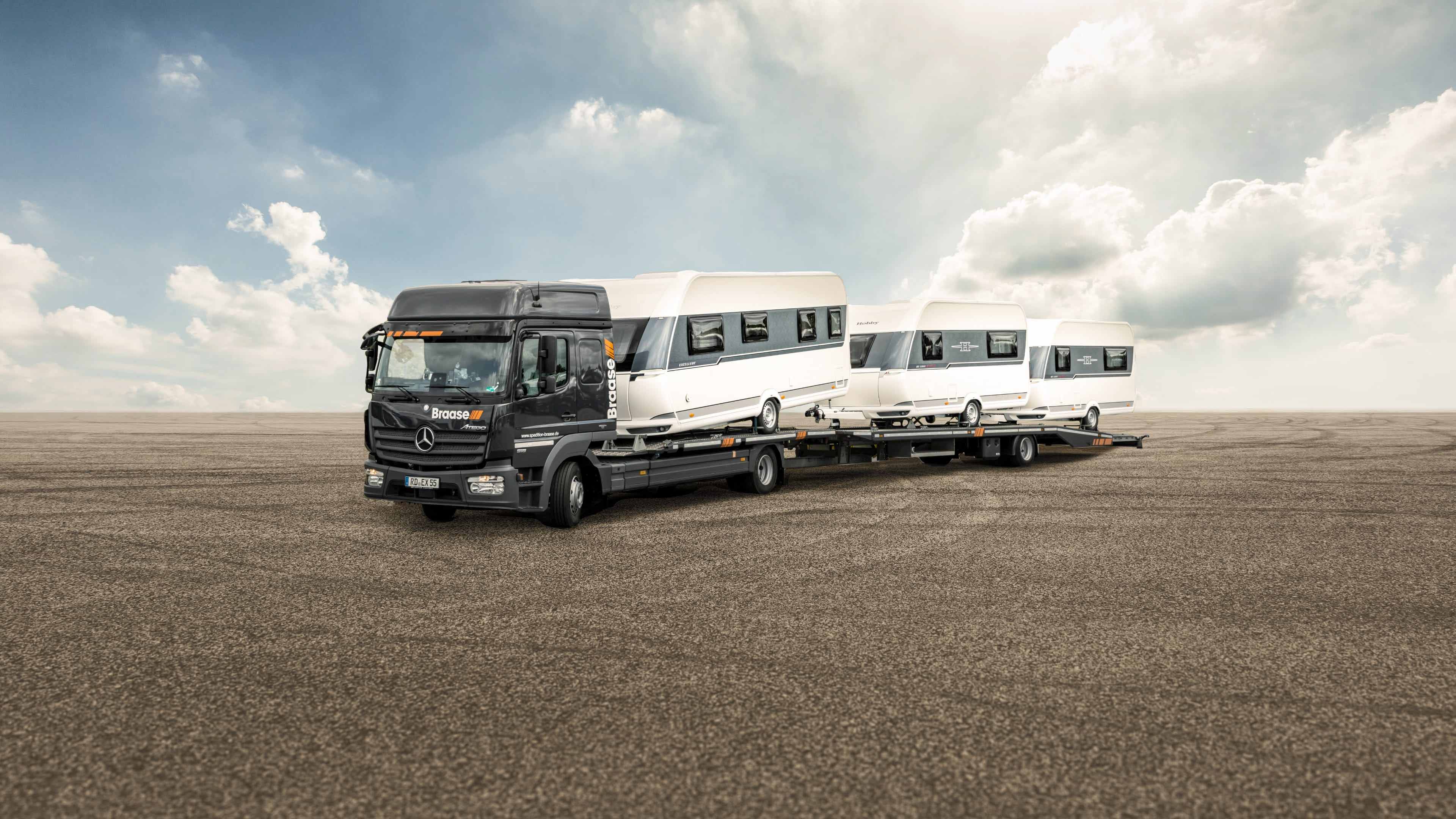 Mit drei Wohnwagen beladener LKW