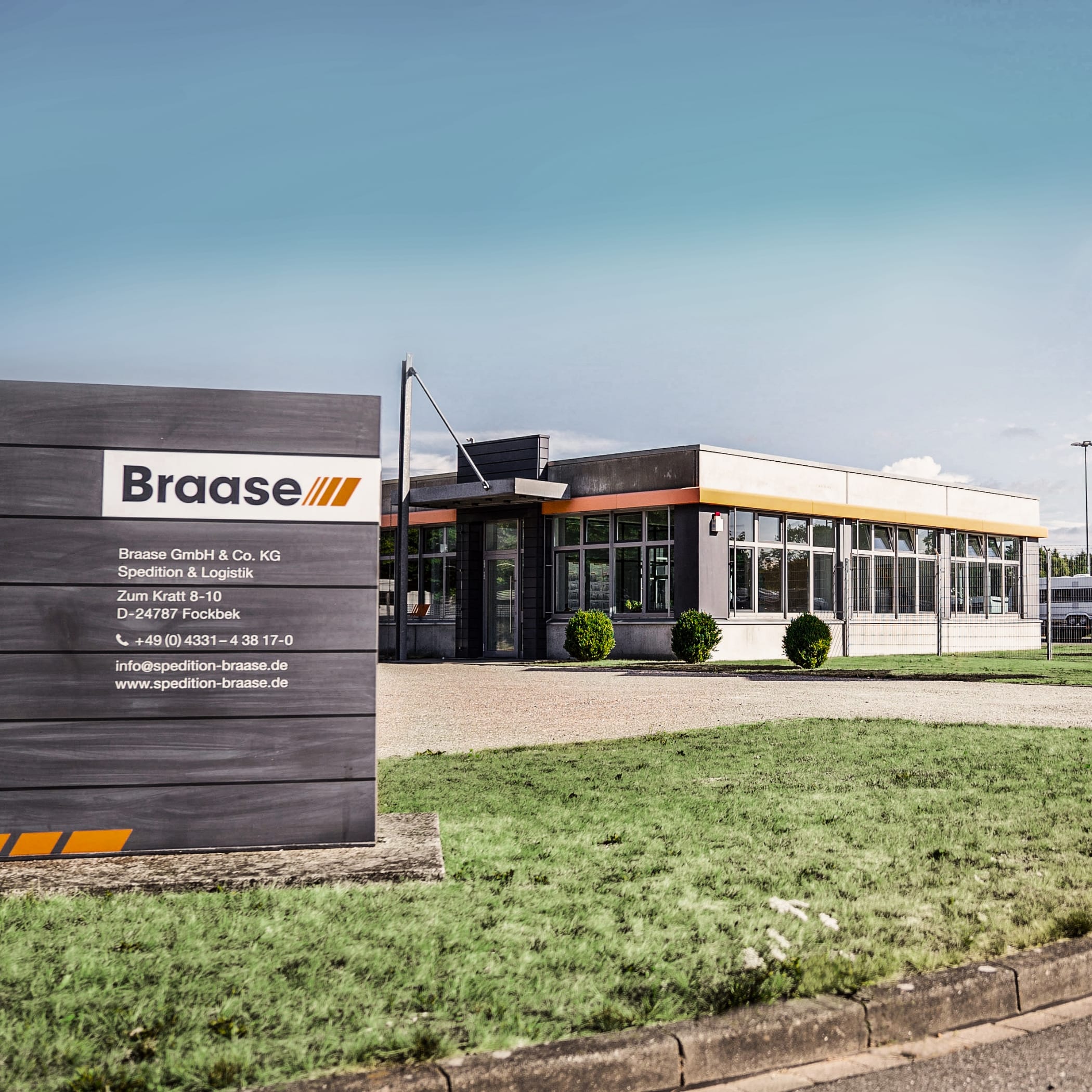 Info-Schild vor Gebäude Spedition Braase unter blauem Himmel