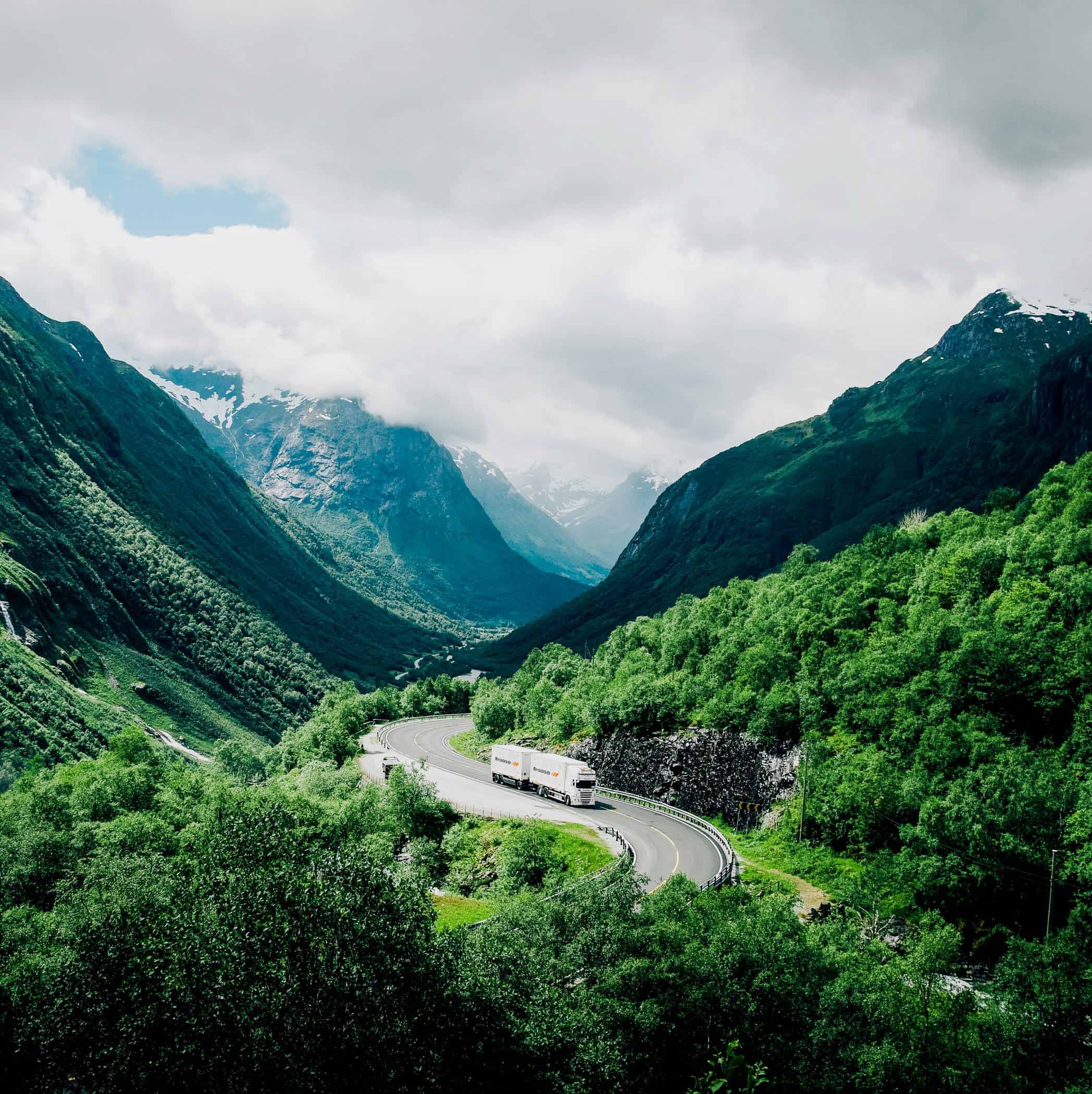 Kurviger Straßenzug in den Bergen auf dem ein weißer Doppellaster der Spedition Braase unterwegs ist