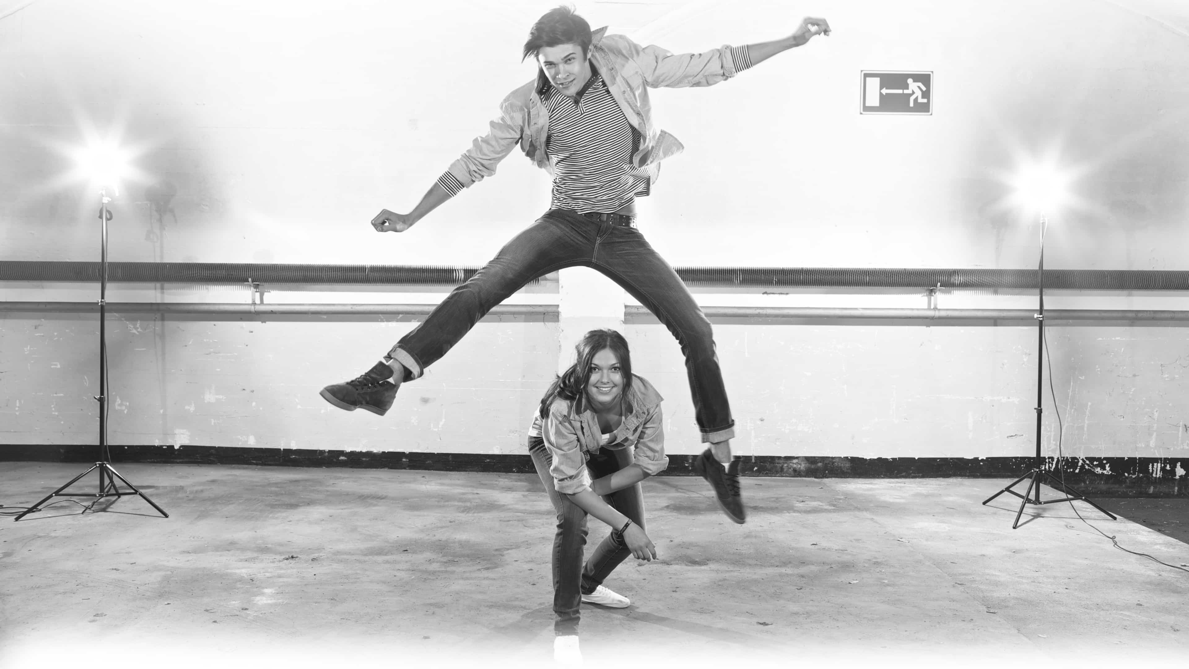 Männliches Model springt über weibliches Model