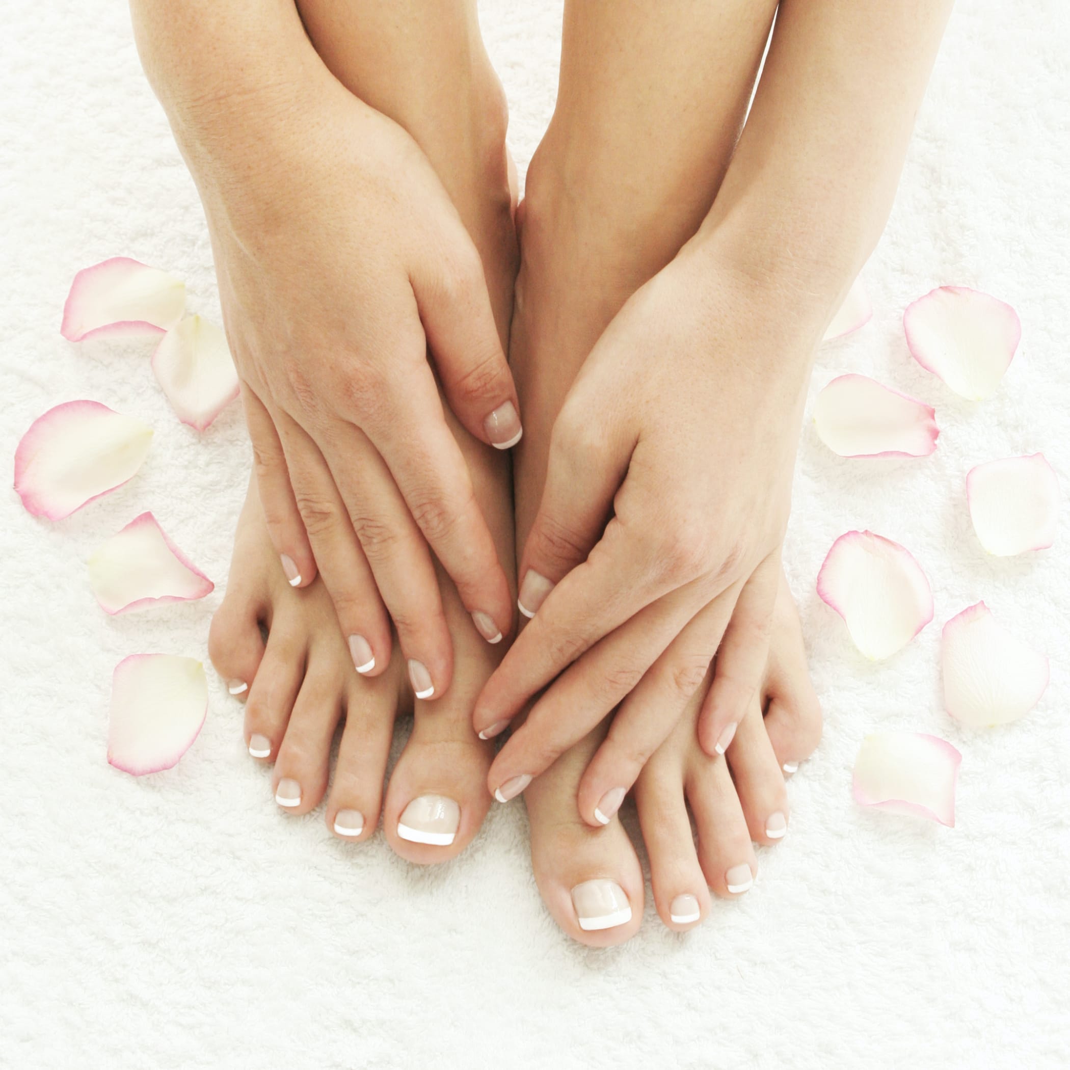 hochzwei_phra_teaser_05.jpg Hände auf Füßen mit gemachten Nägeln umgeben von Rosenblättern