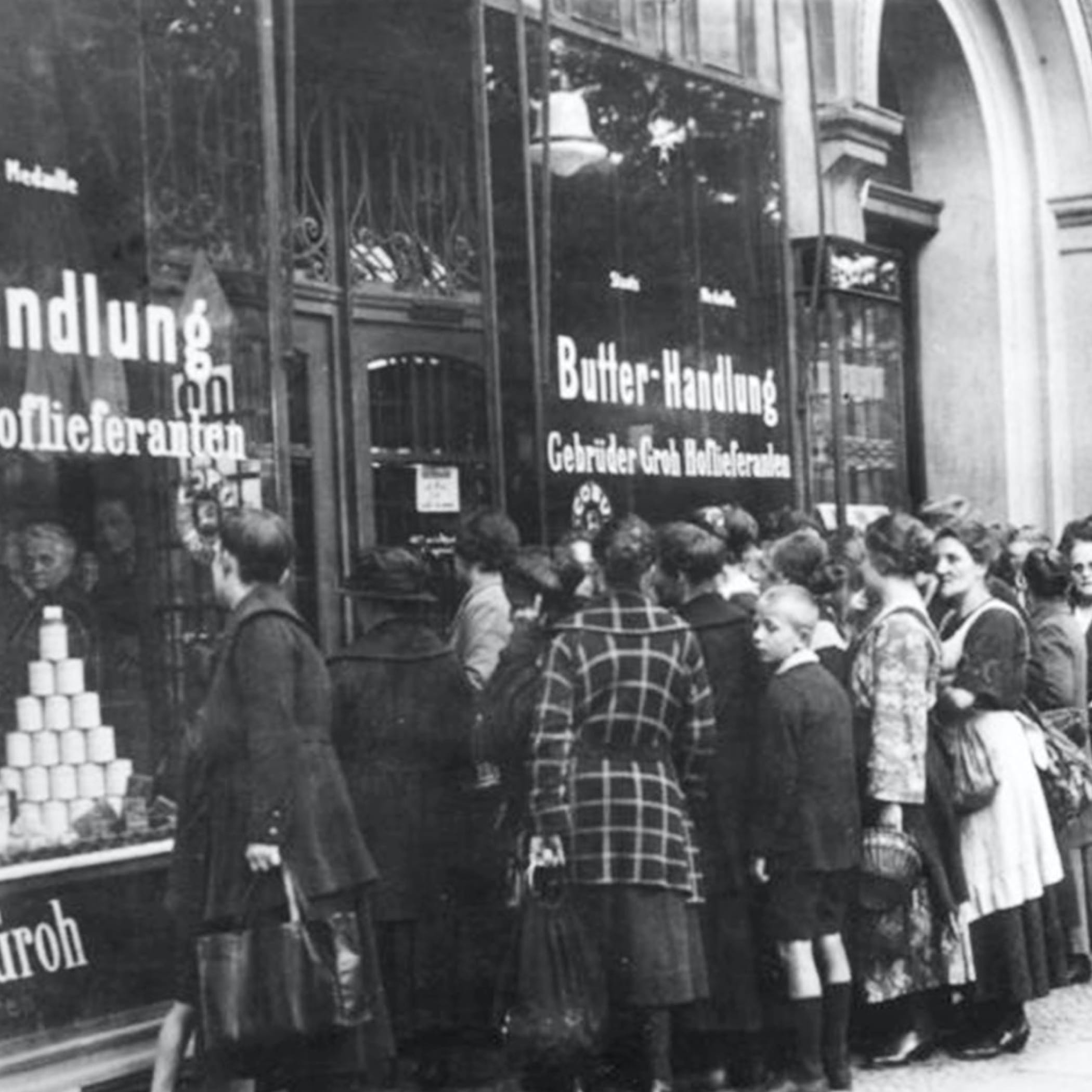 hochzwei_cred_teaser_05.jpg Alte Schwarz-Weiß-Aufnahme einer Warteschlange von Frauen und Kindern vor einer Butter-Handlung