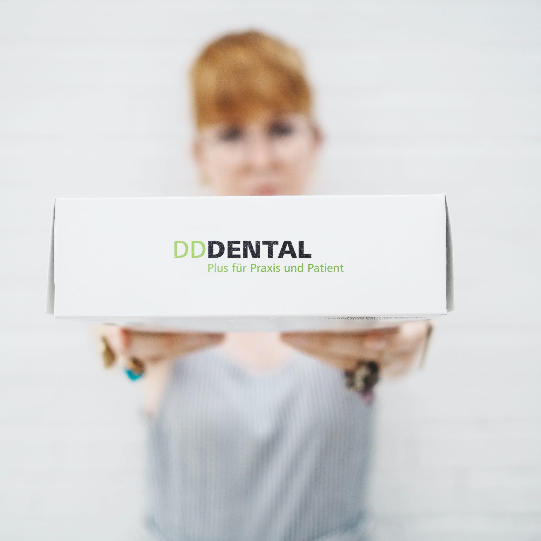 hochzwei_ddd_teaser_01_hauptteaser.jpg Frau hält weißes Paket mit Logo DD Dental