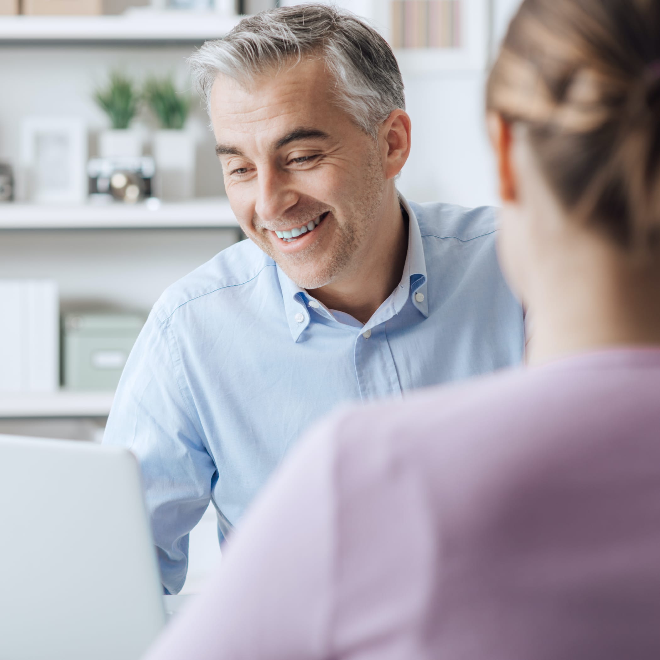 hochzwei_dede_teaser_04.jpg Blick über die Schulter einer Person im rosa Pullover auf einen lächelnden Mann im hellblauen Hemd