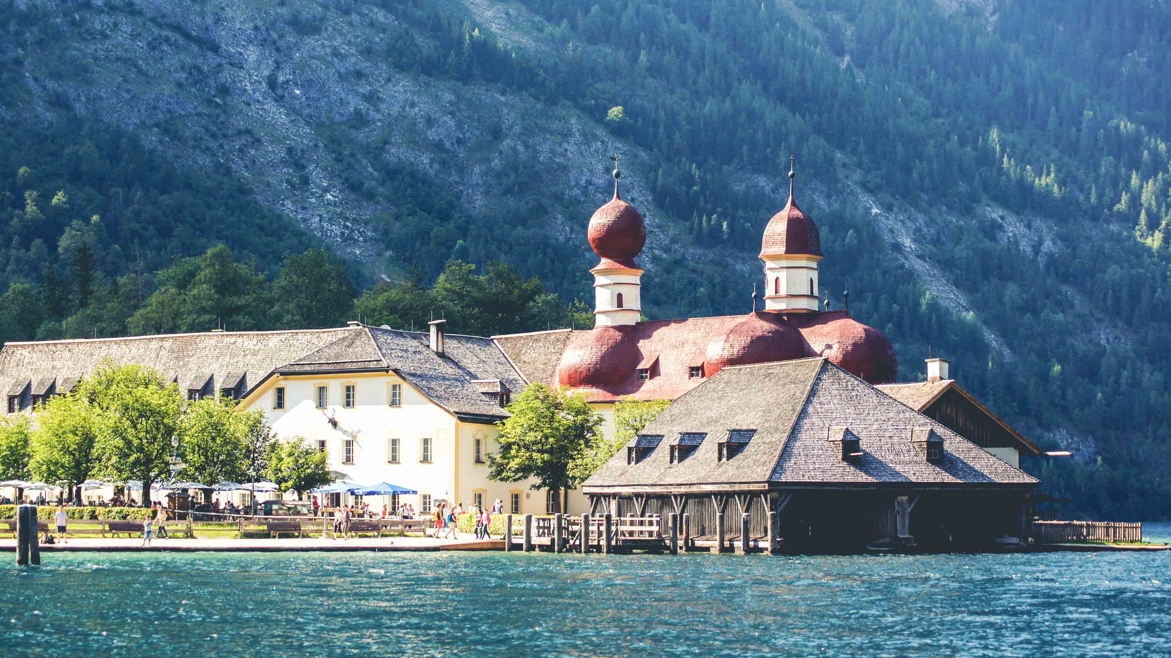 Großes Gebäudkomplex direkt an einem Bergsee, Waldhang im Hintergrund
