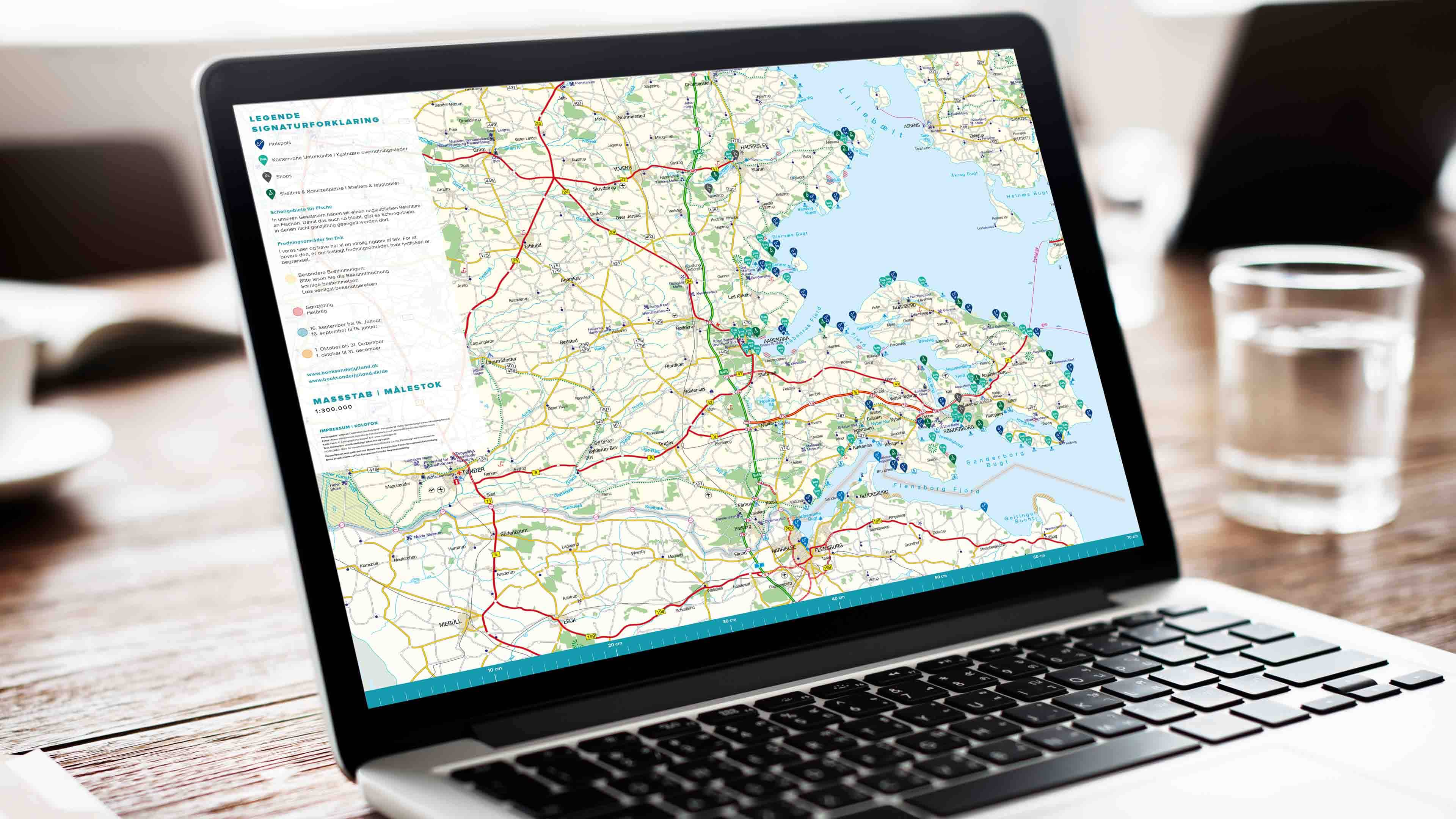 hochzwei_deso_slider_02.jpg Laptop zeigt Karte vom deutsch-dänischen Grenzgebiet mit Verortungsicons an der Ostsee