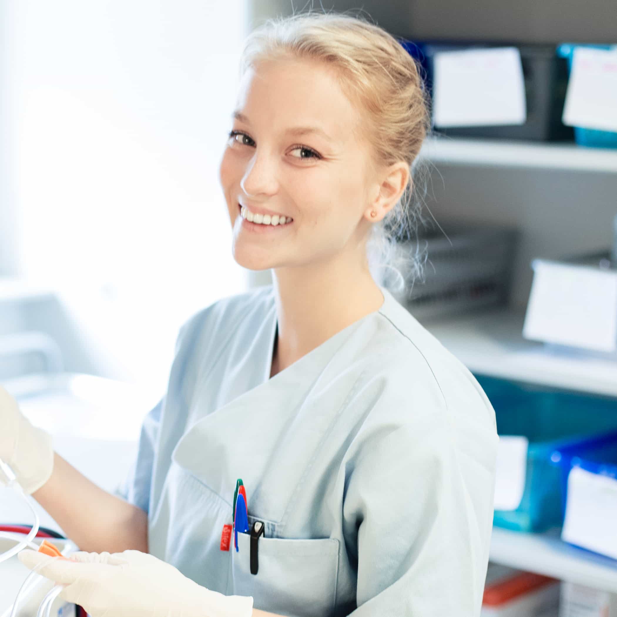 hochzwei_diako_teaser_02.jpg Lächelnde Blondine im Pflegehemd bei der Arbeit