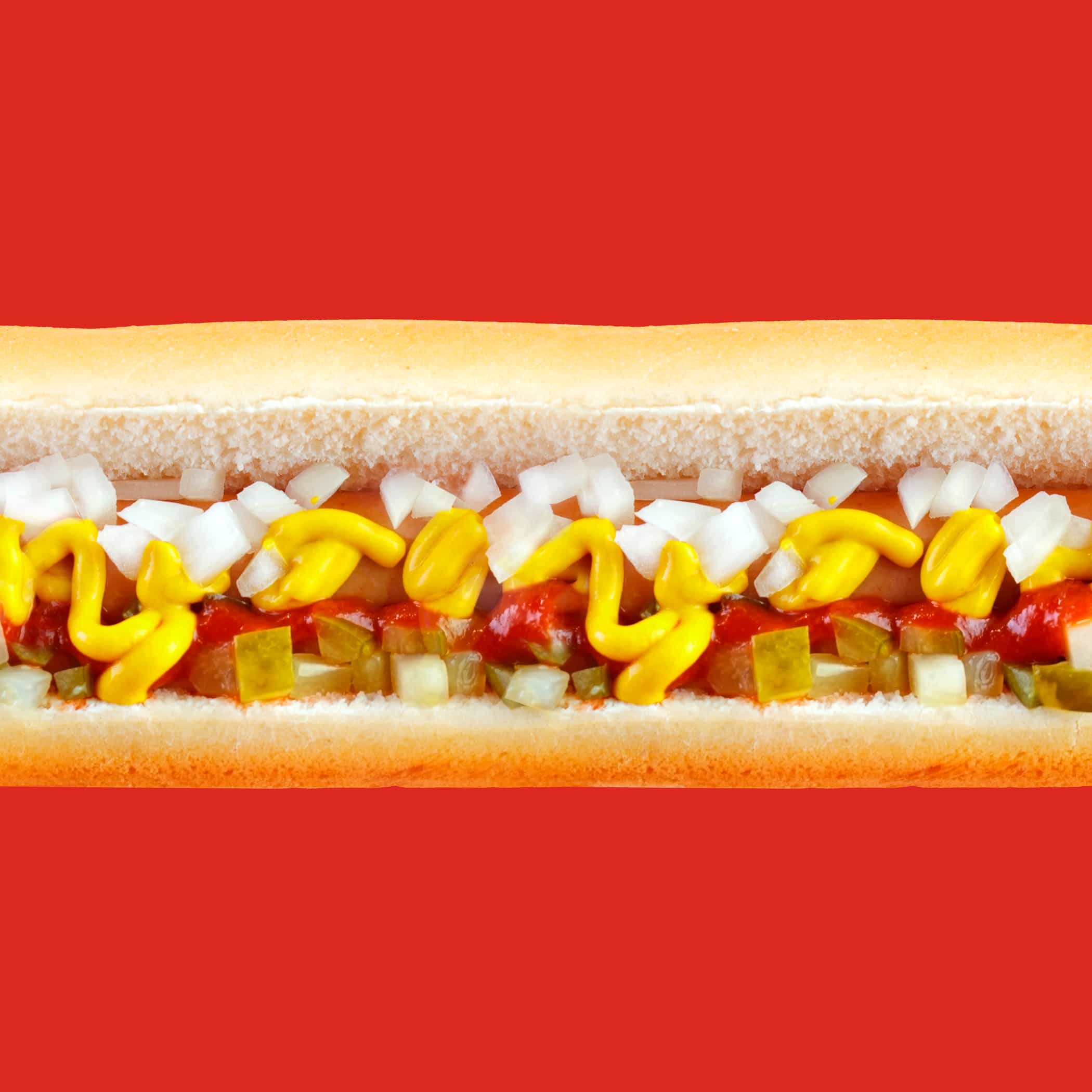 hochzwei_sfdw_teaser_11.jpg Mittelstück 2 eines mit Zwiebel- und Gurkenstücken sowie Senf belegten Hotdogs vor rotem Hintergrund