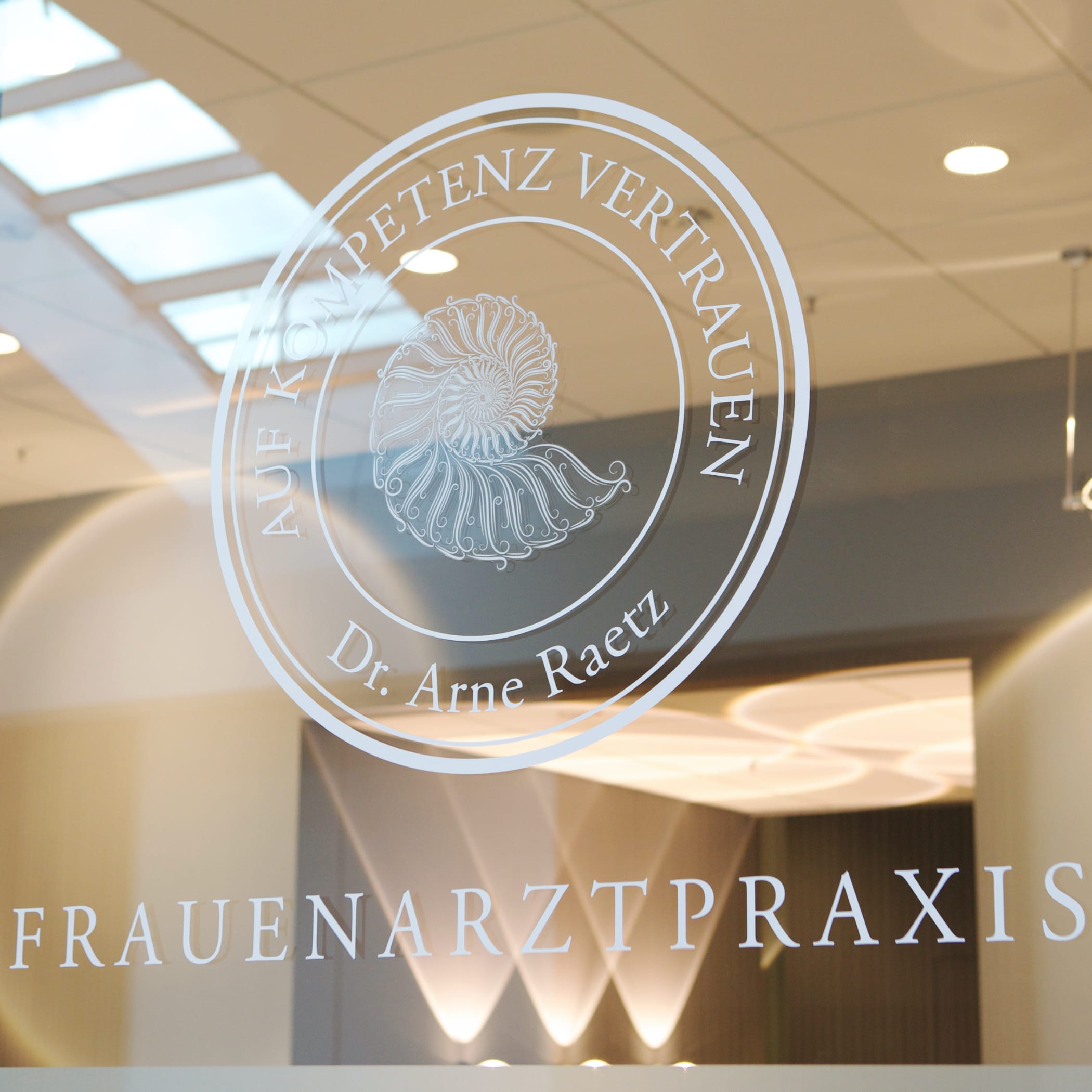 hochzwei_rae_teaser_01.jpg Rundes Logo der Frauenarztpraxis Dr. Arne Raetz auf Glasscheibe