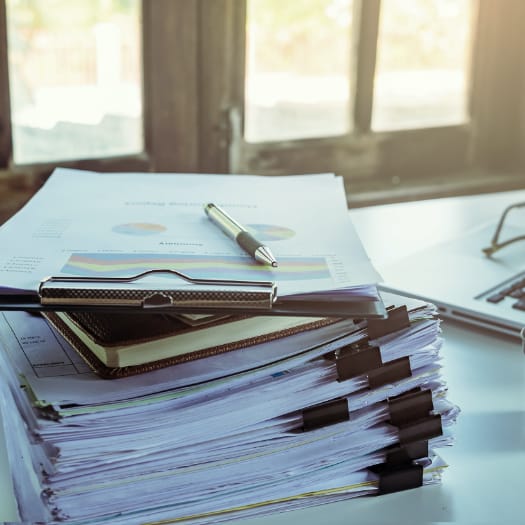 hochzwei_egeb_teaser_08.jpg Stapel mit Geschäftsunterlagen, Klemmbrett und Kugelschreiber auf Tisch