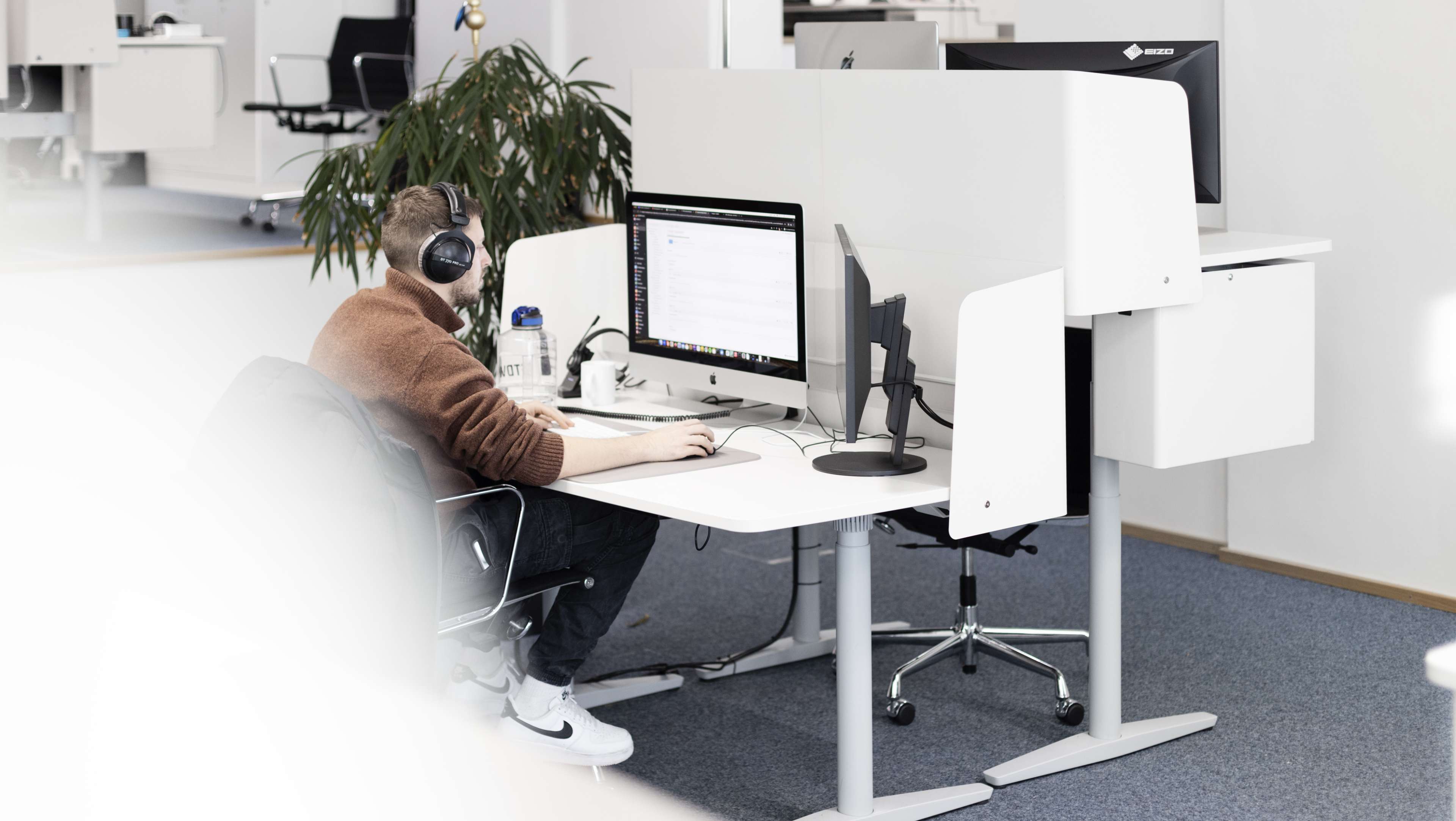 HOCHZWEI-Mitarbeiter arbeitet konzentriert am Schreibtisch mit zwei Bildschirmen