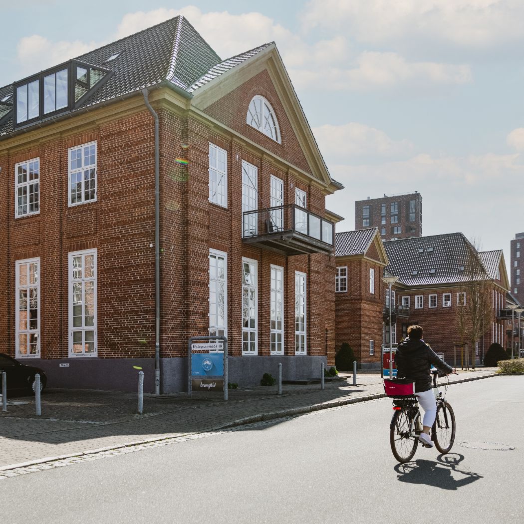 HOCHZWEI-Gebäude in Sonwik von außen, eine Fahrradfahrerin fährt vorbei